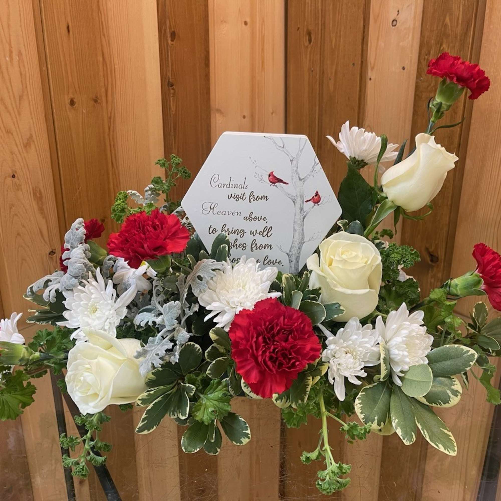 Red carnations and white roses arranged around a memorial plaque