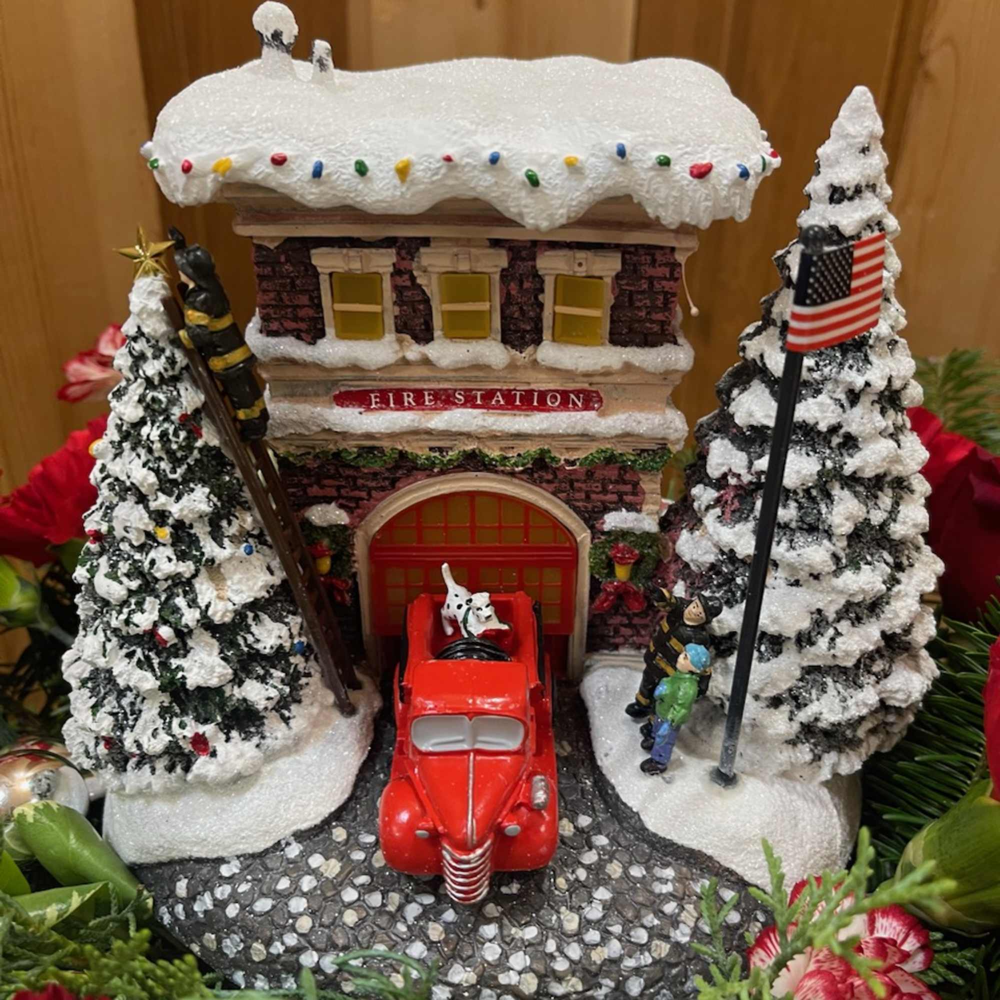 Miniature snow-covered fire station with a red truck and small trees