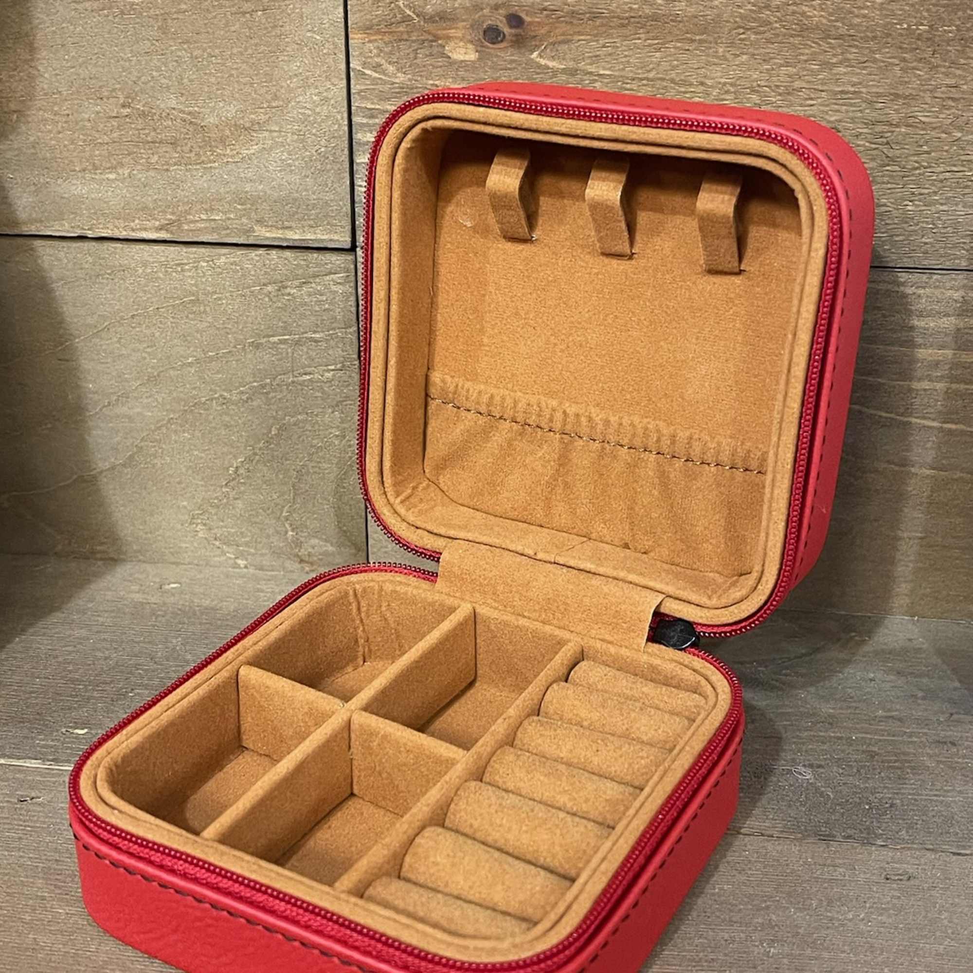 Open red zippered jewelry case with tan compartments