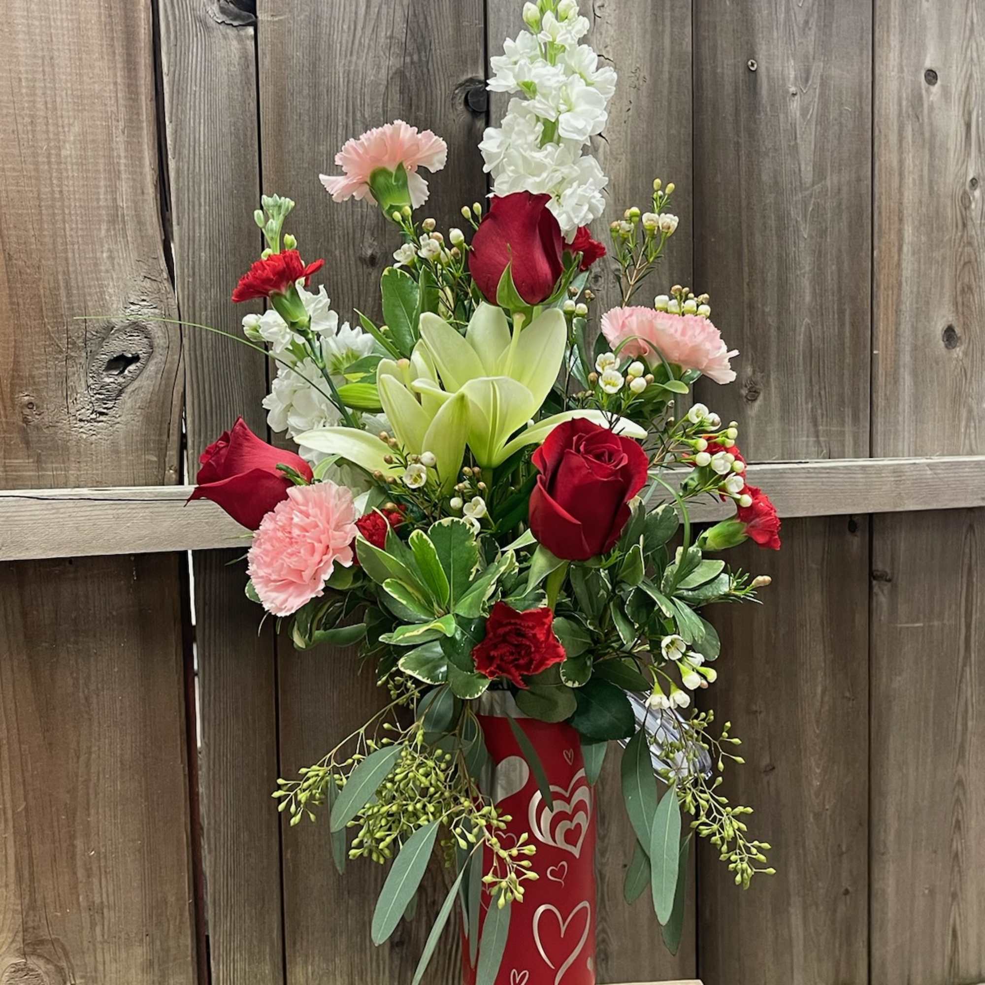 Red roses and white lilies in a red vase with heart designs
