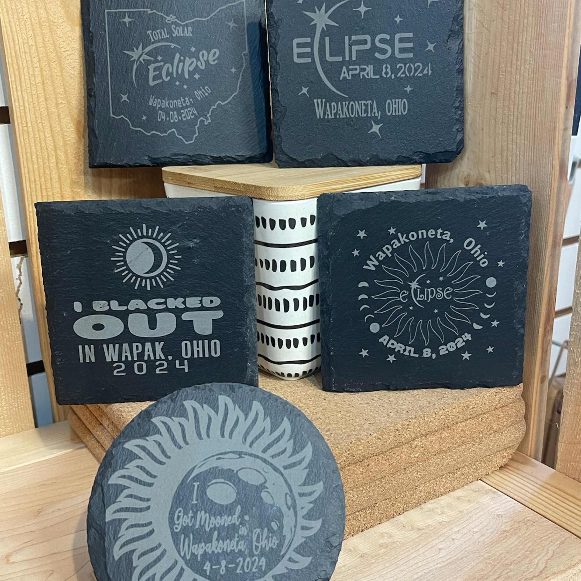 Decorative slate coasters with eclipse-themed designs and a small patterned container