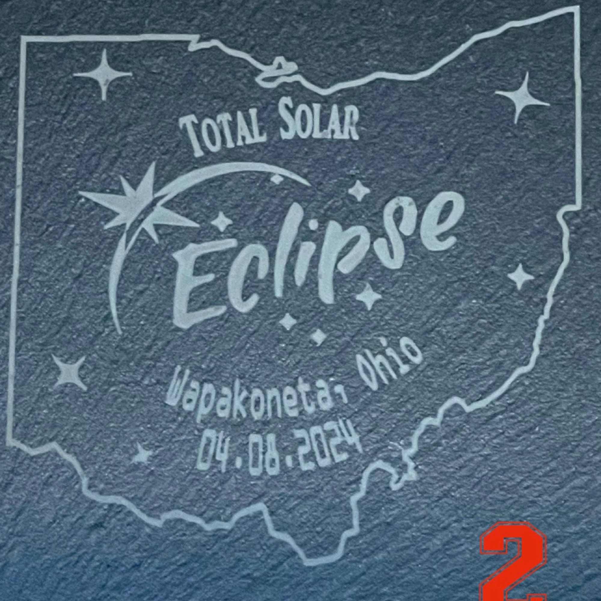 Printed Eclipse graphic with Ohio outline and date text on a dark textured surface