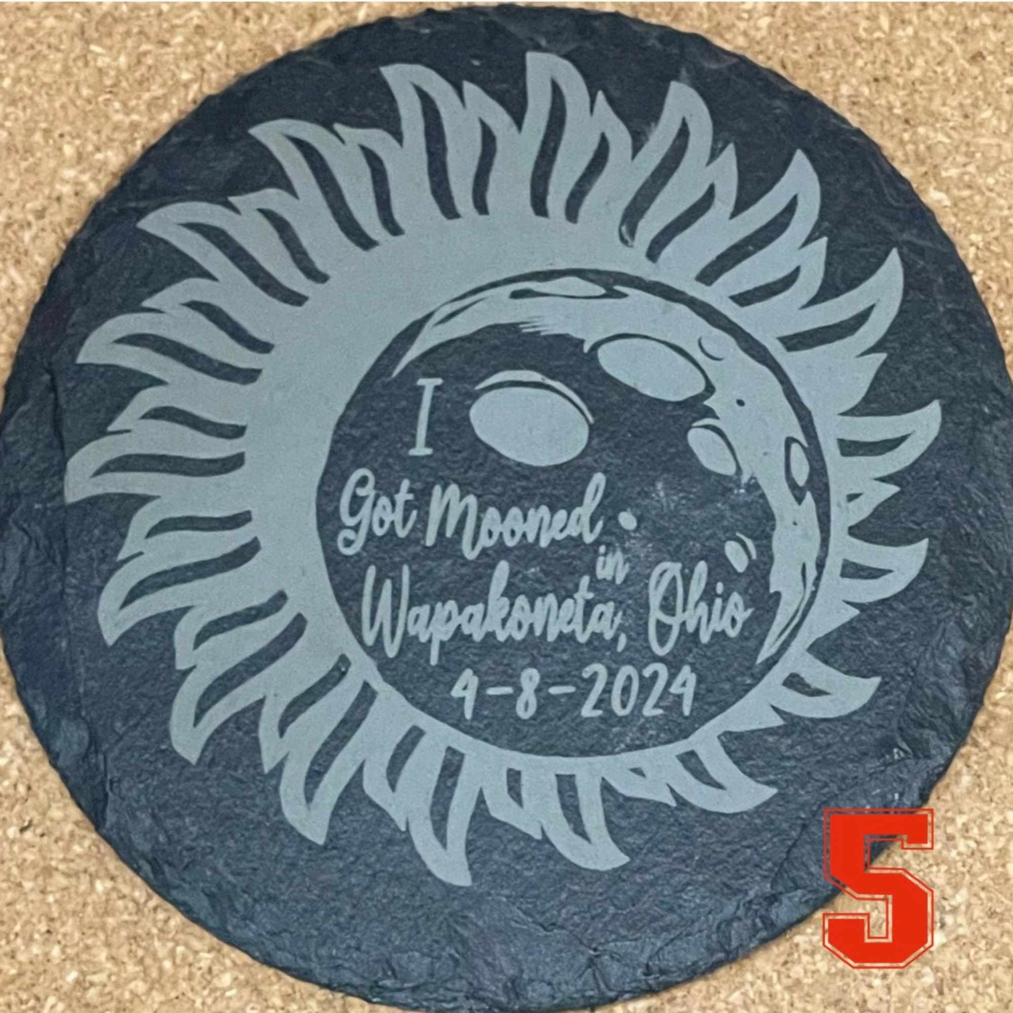 Round black stone plaque with a moon and sun design and text
