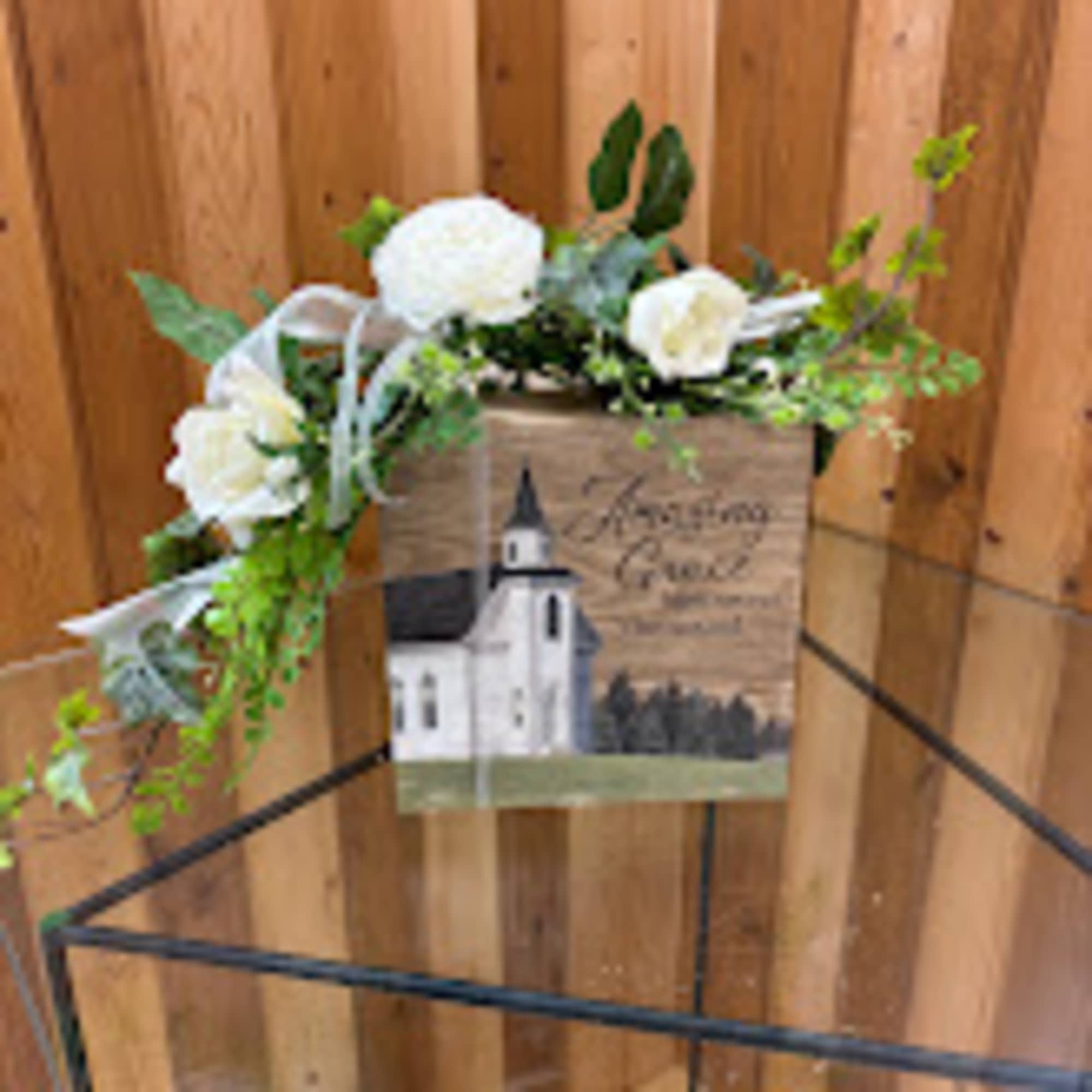 White floral wreath on a wooden sign with a church illustration
