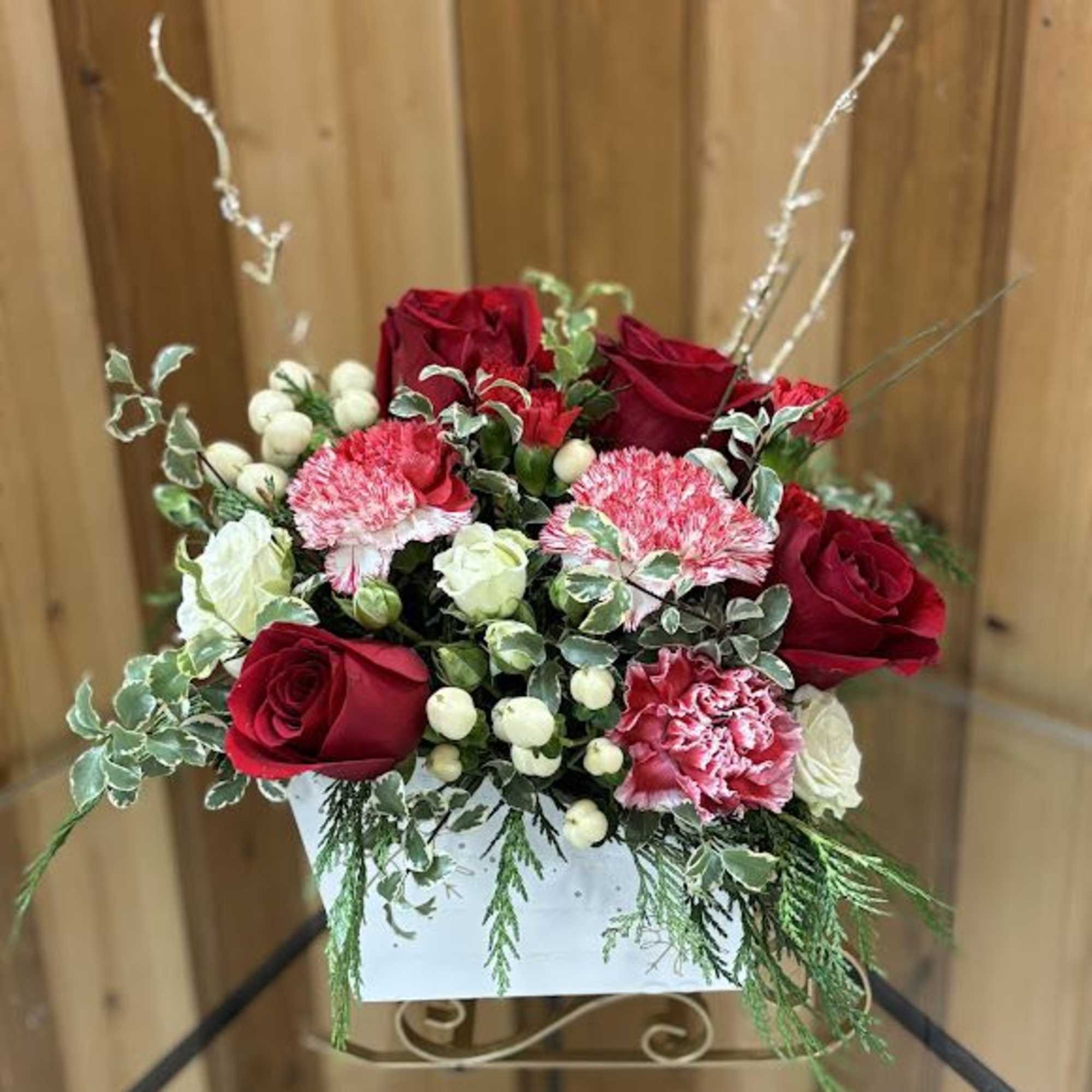 Red roses and pink carnations in a white container