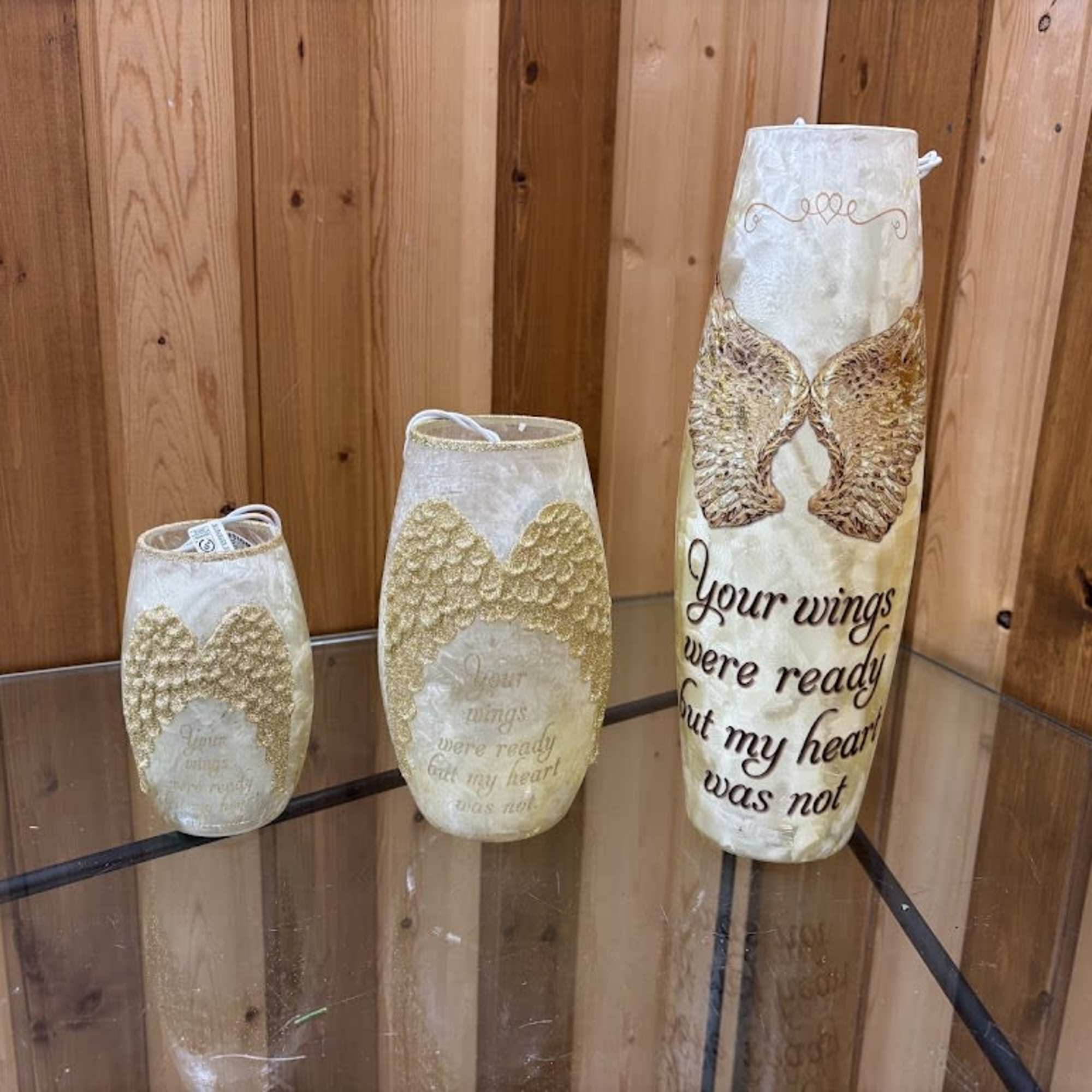Three decorative memorial candle holders with angel wings and text