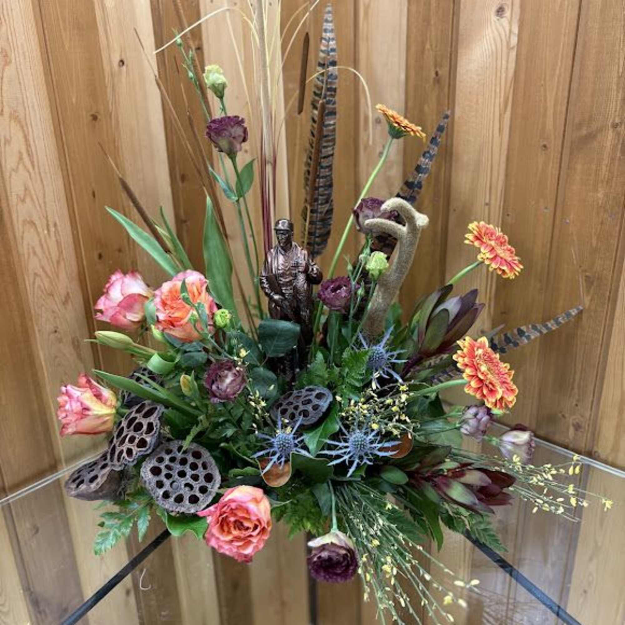 Mixed floral arrangement with orange and purple blooms in a glass vase