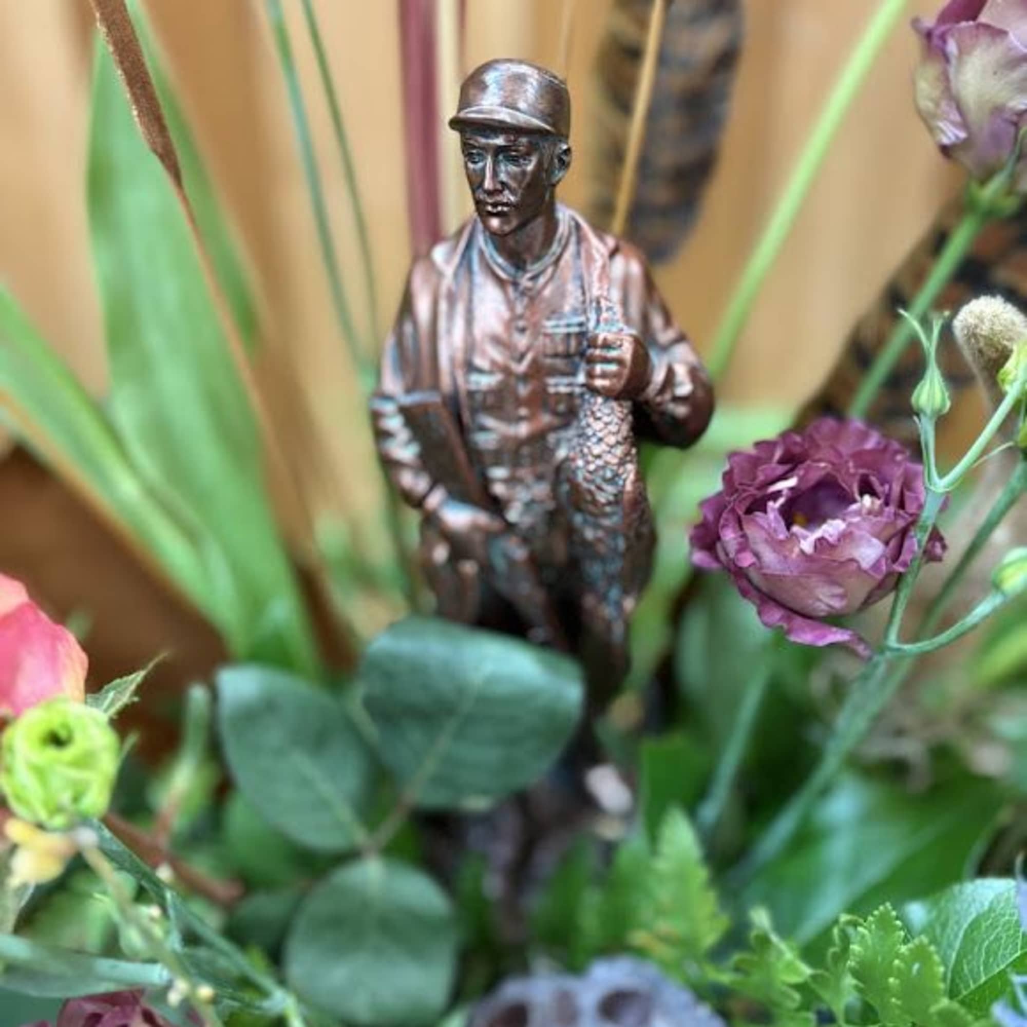 Floral arrangement with a small fisherman figurine and purple blooms