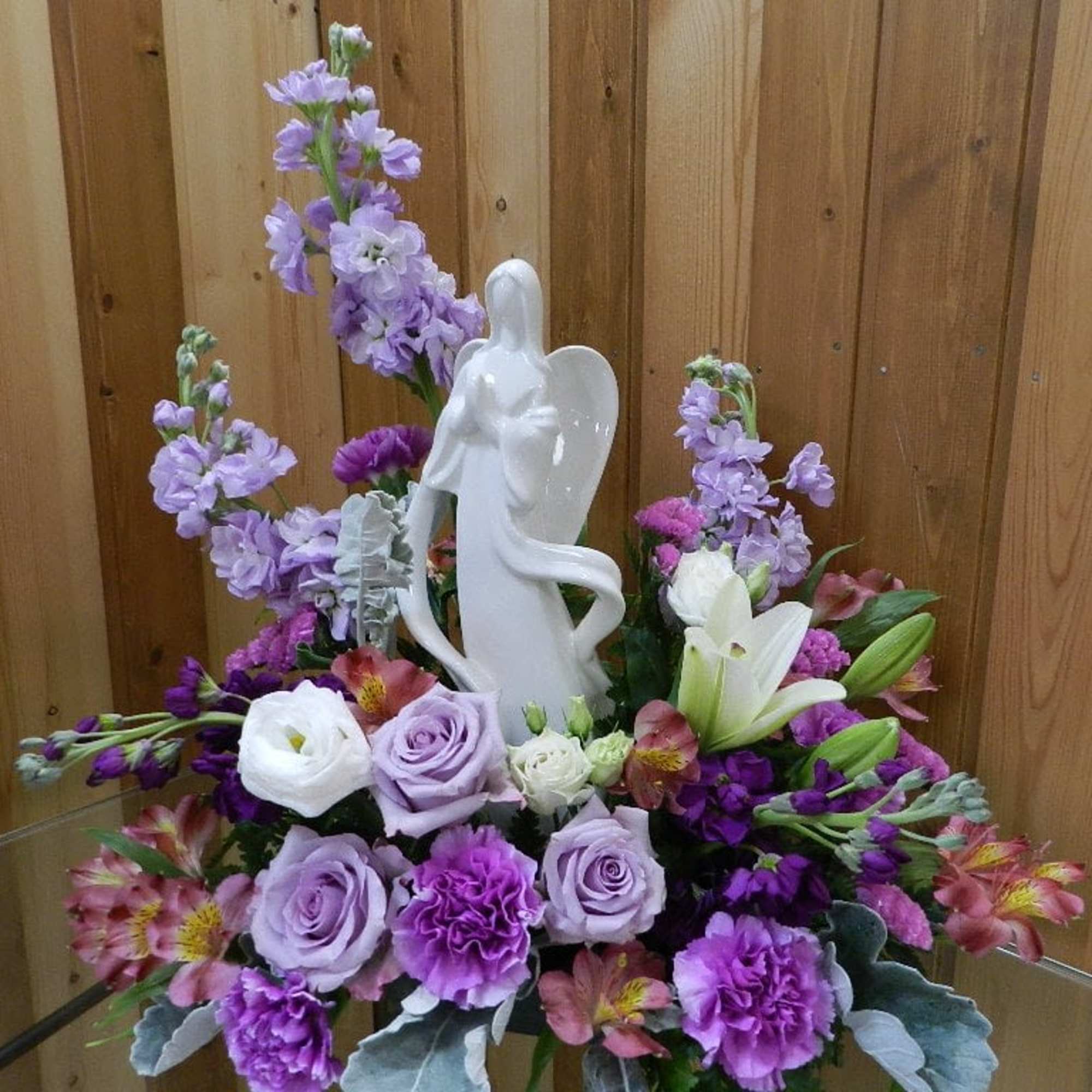 Purple and white floral arrangement with an angel figurine