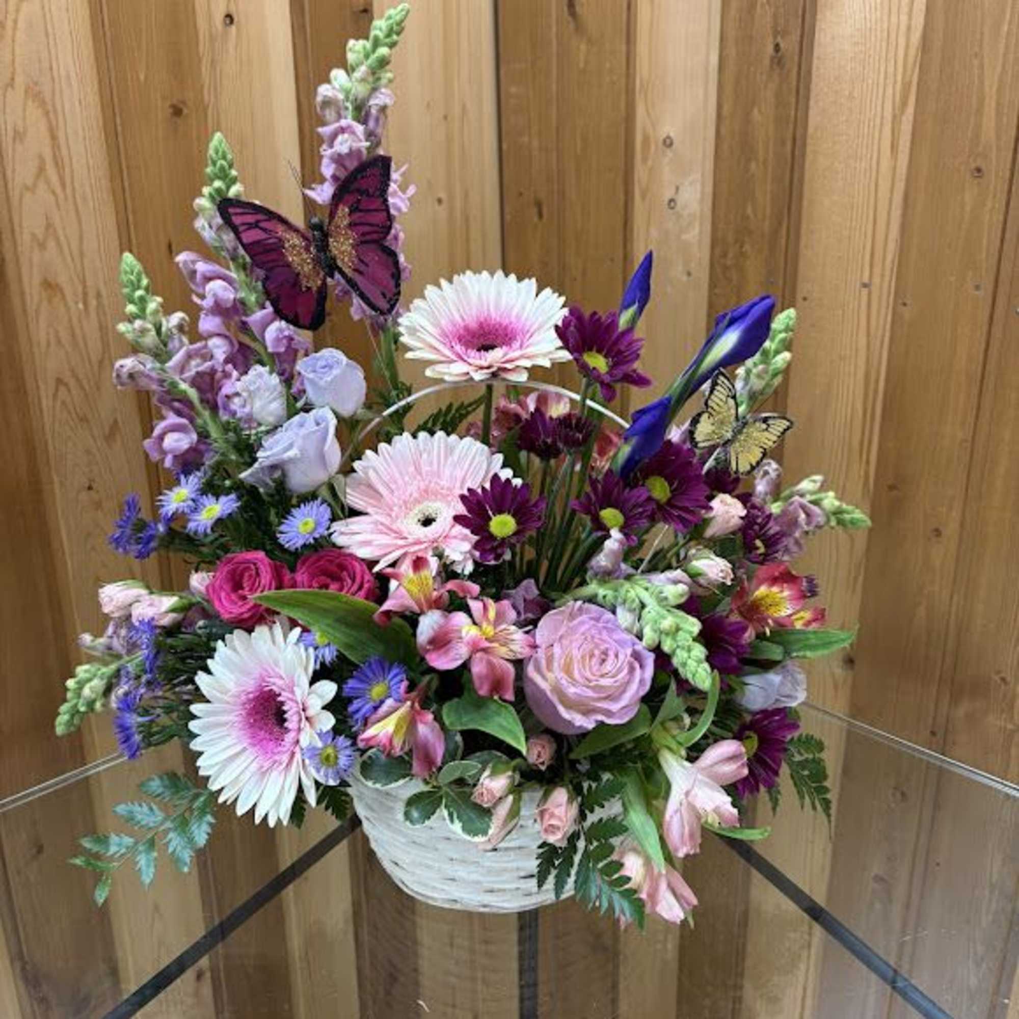Mixed bouquet in a white basket with pink, purple, and white flowers