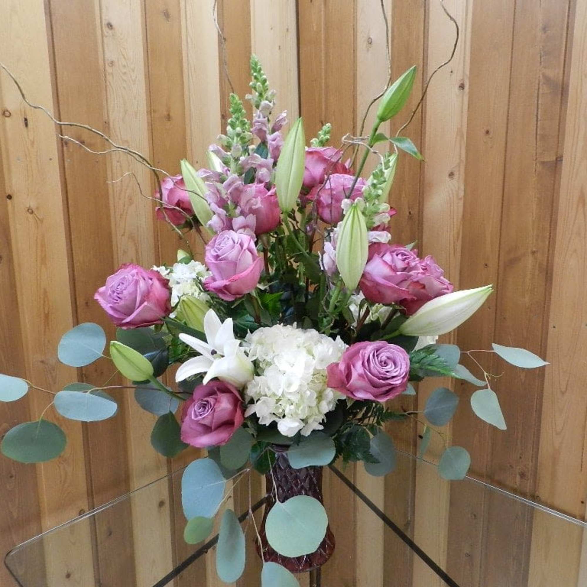Pink roses and white lilies arranged in a vase with airy branches