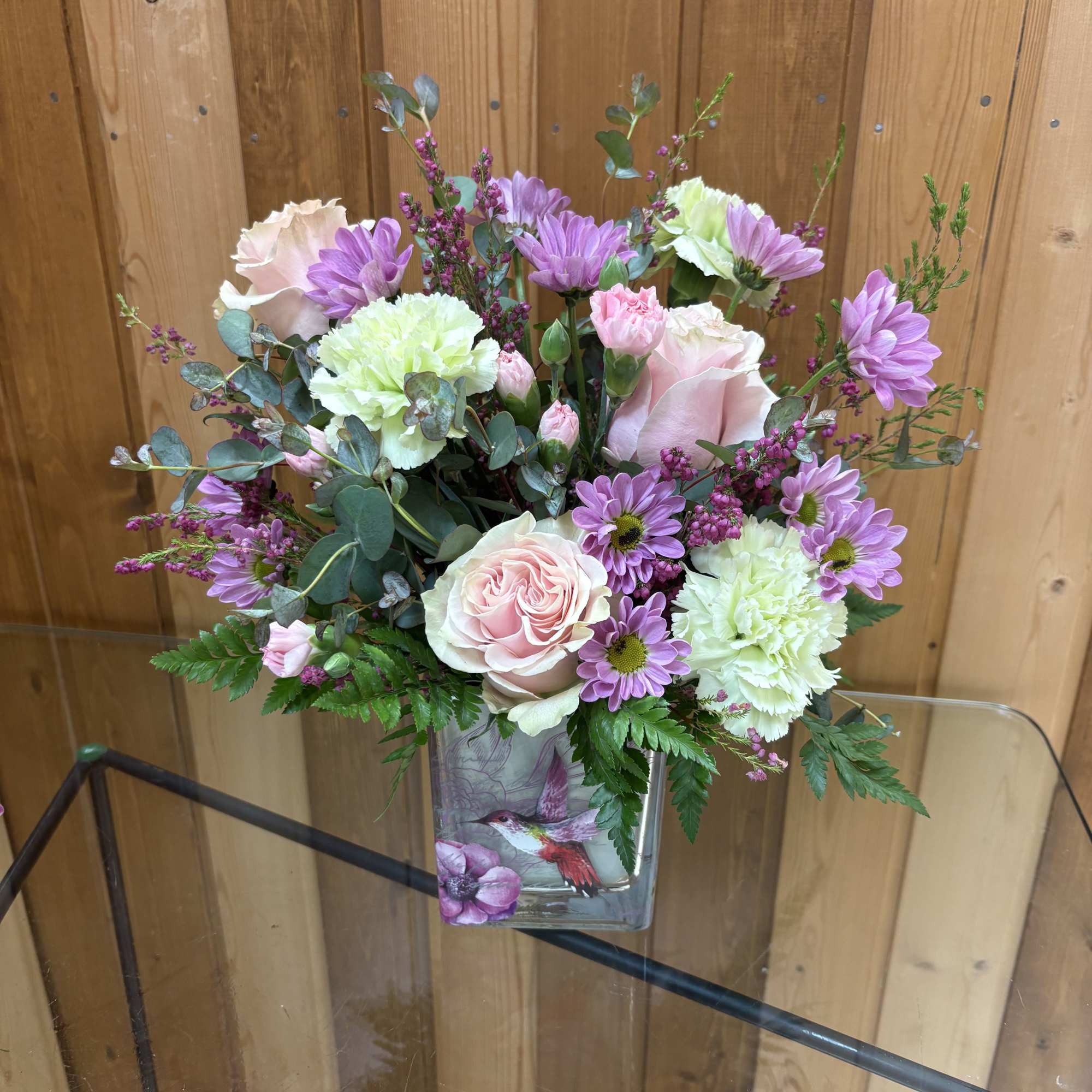 Bouquet of pink and lavender flowers in a square glass vase