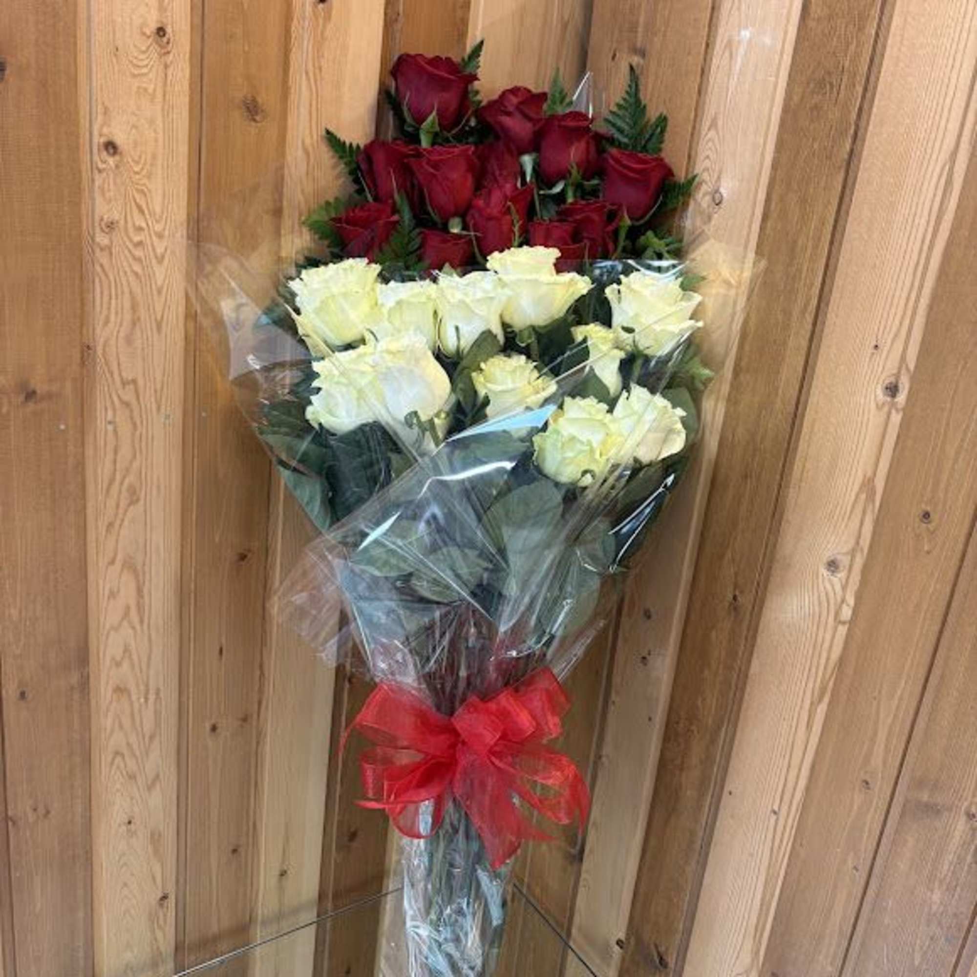Bouquet of red and pale yellow roses wrapped in clear plastic with a red bow