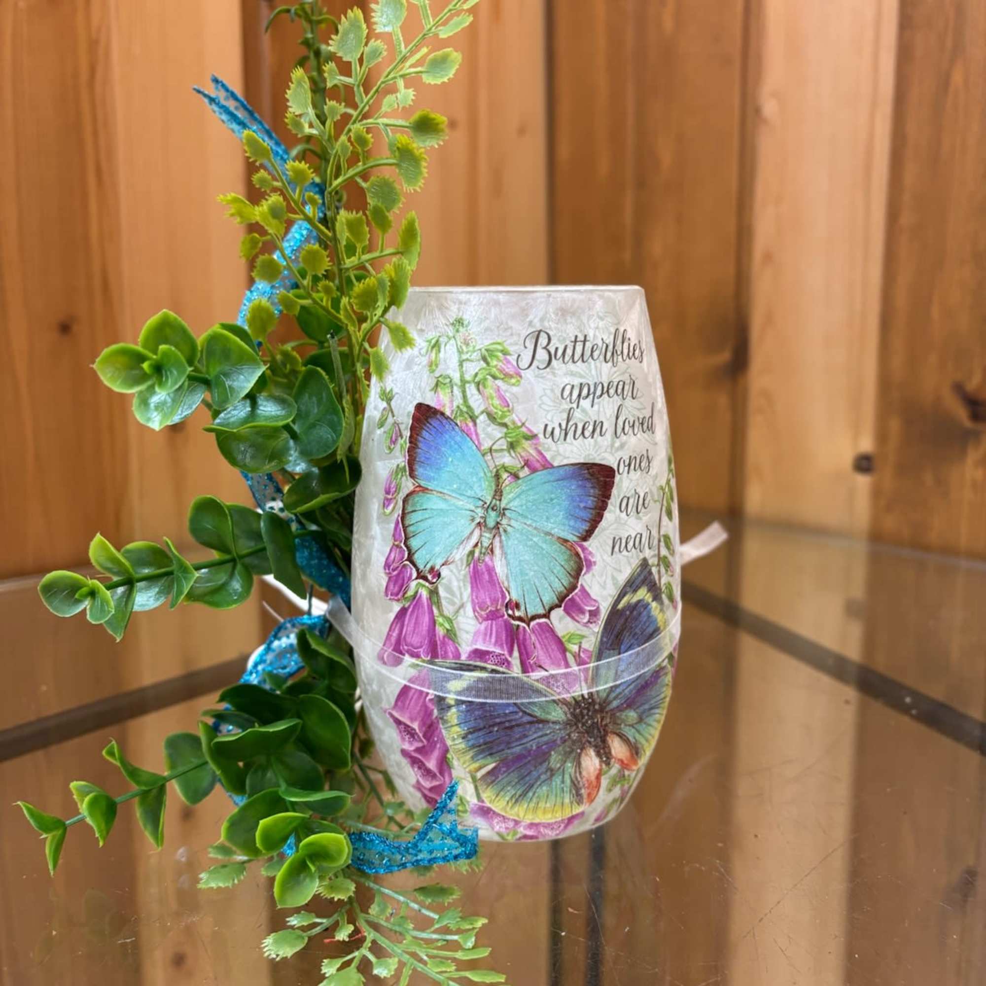 Butterfly-themed decorative vase with faux greenery and blue ribbon