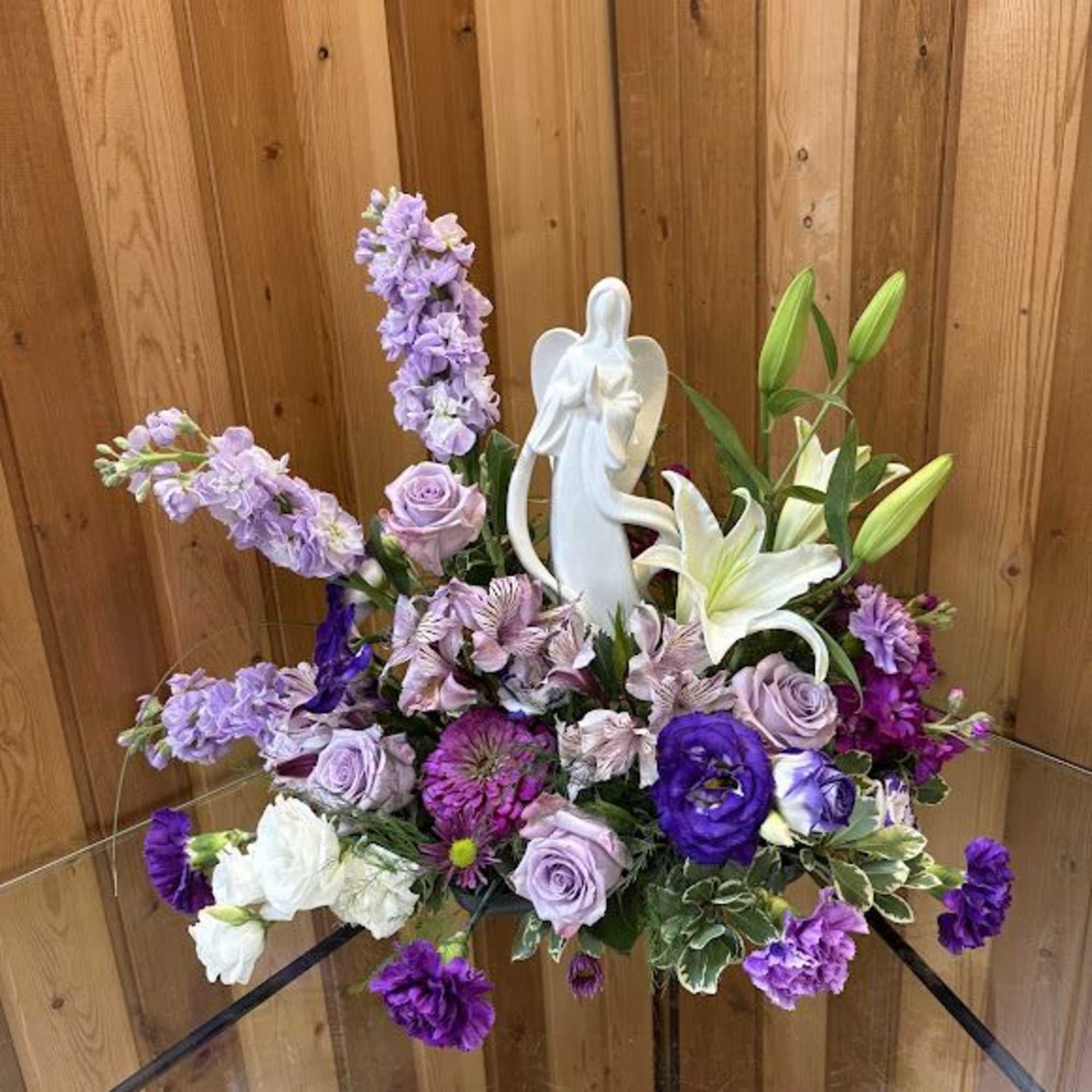Purple and white floral arrangement with a white angel figurine