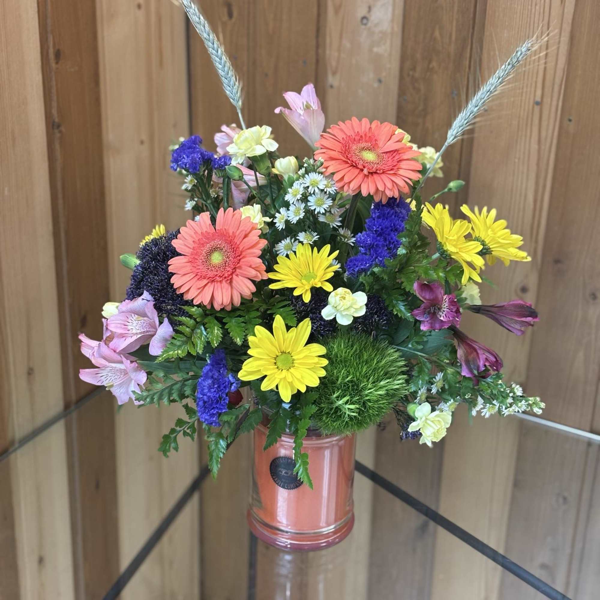 Mixed bouquet in a pink glass jar with bright gerbera daisies