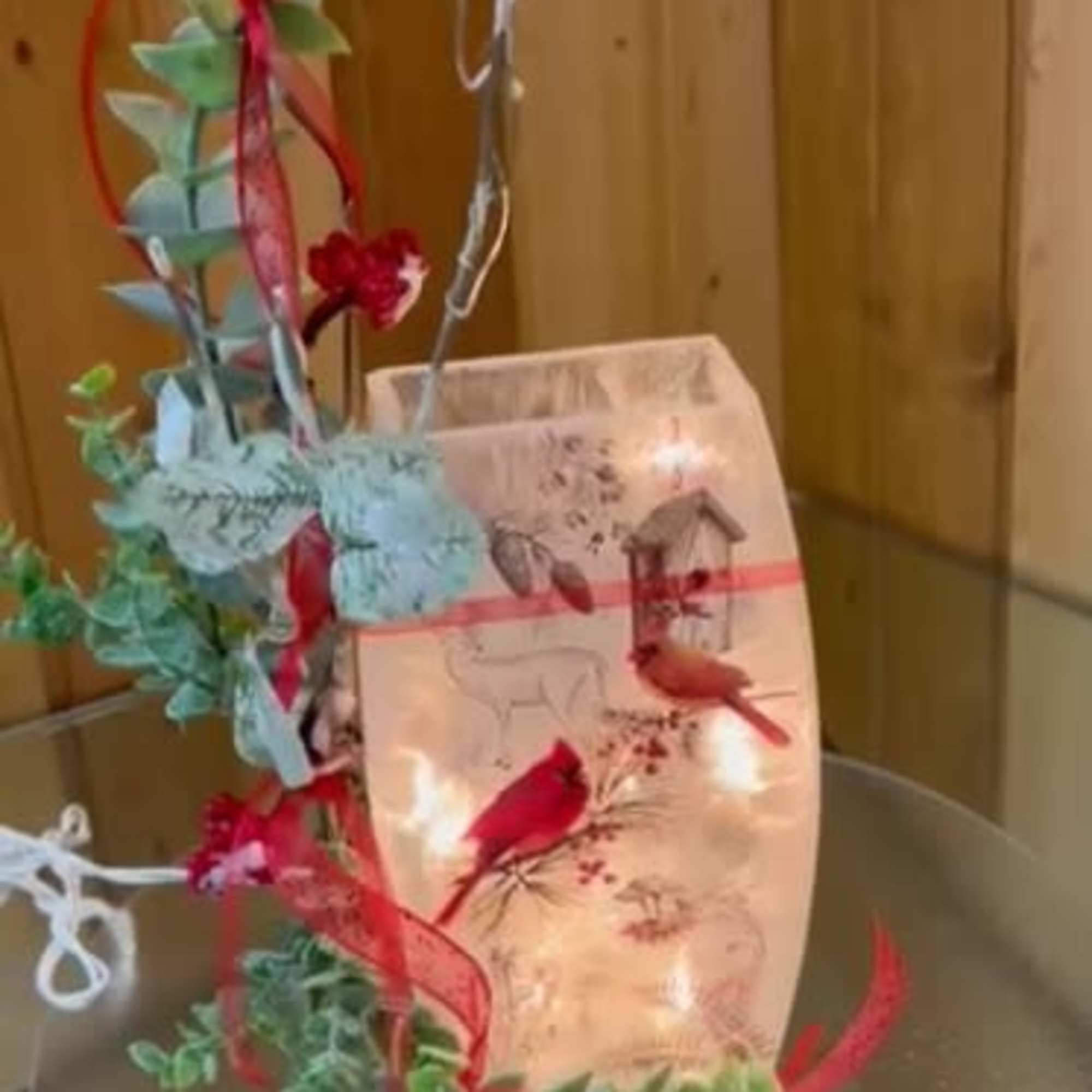 Decorative arrangement with red birds and eucalyptus on a clear stand