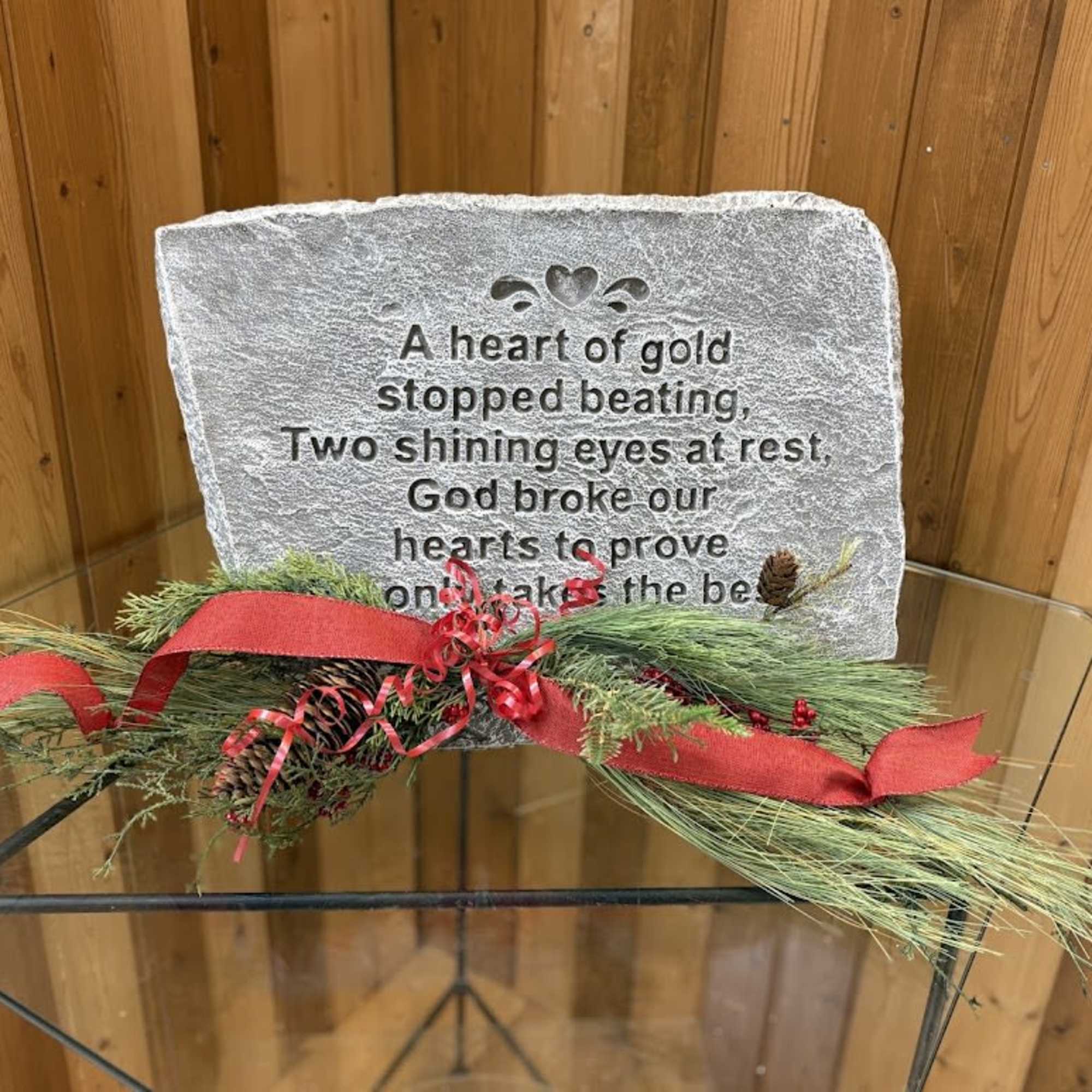 Memorial stone with engraved text and red ribbon on evergreen garland