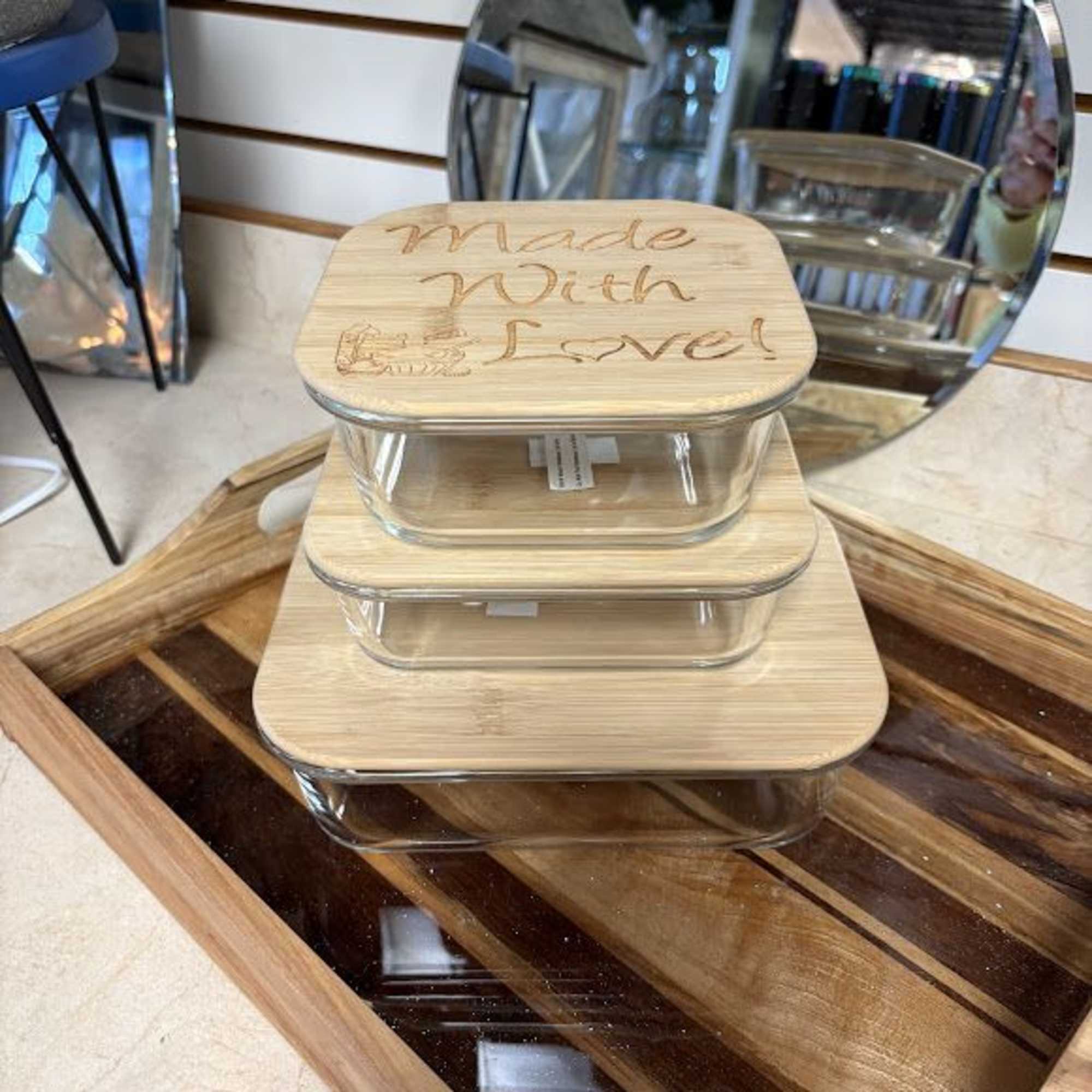 Stacked glass food containers with bamboo lids on a wooden tray