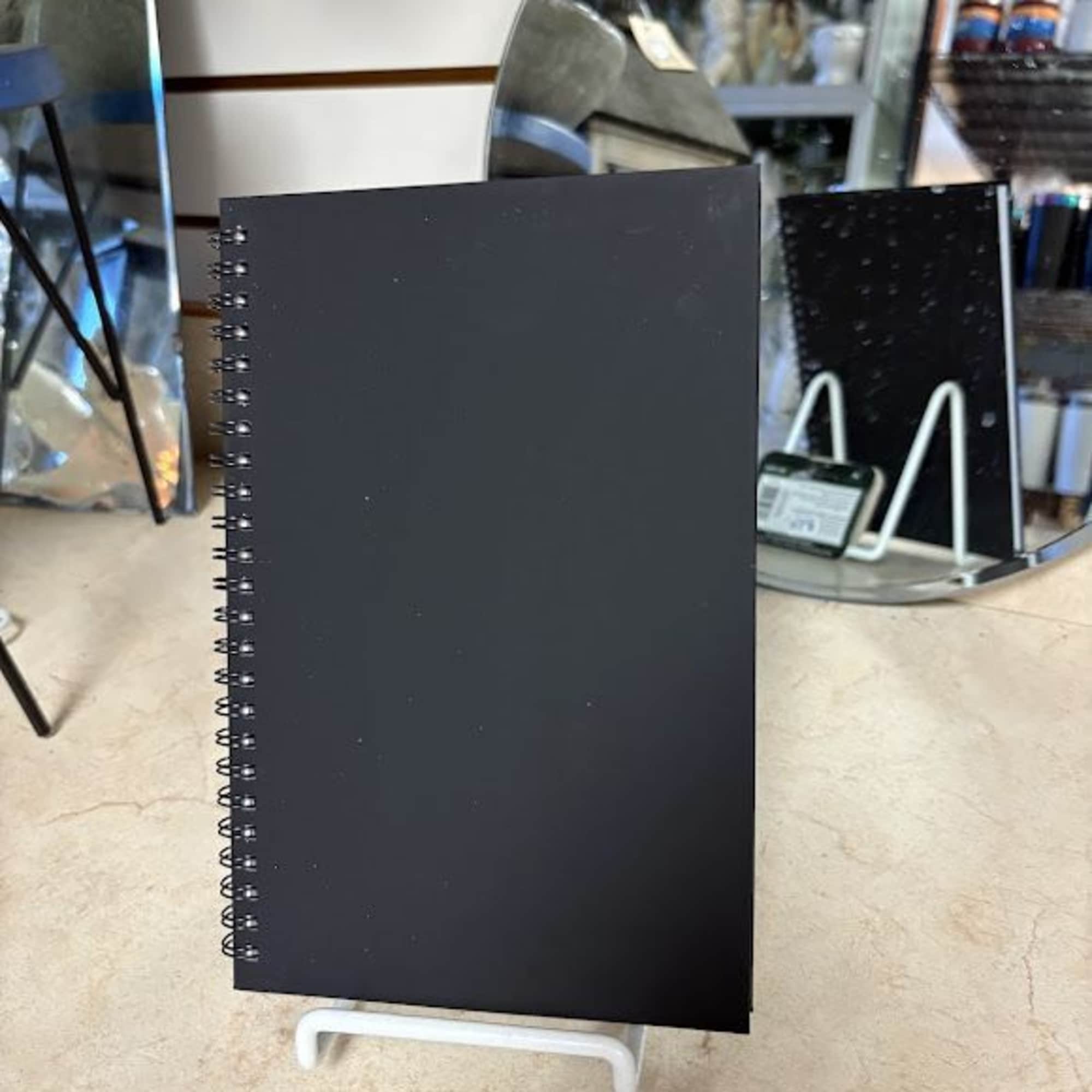 Black spiral-bound display board on a white stand