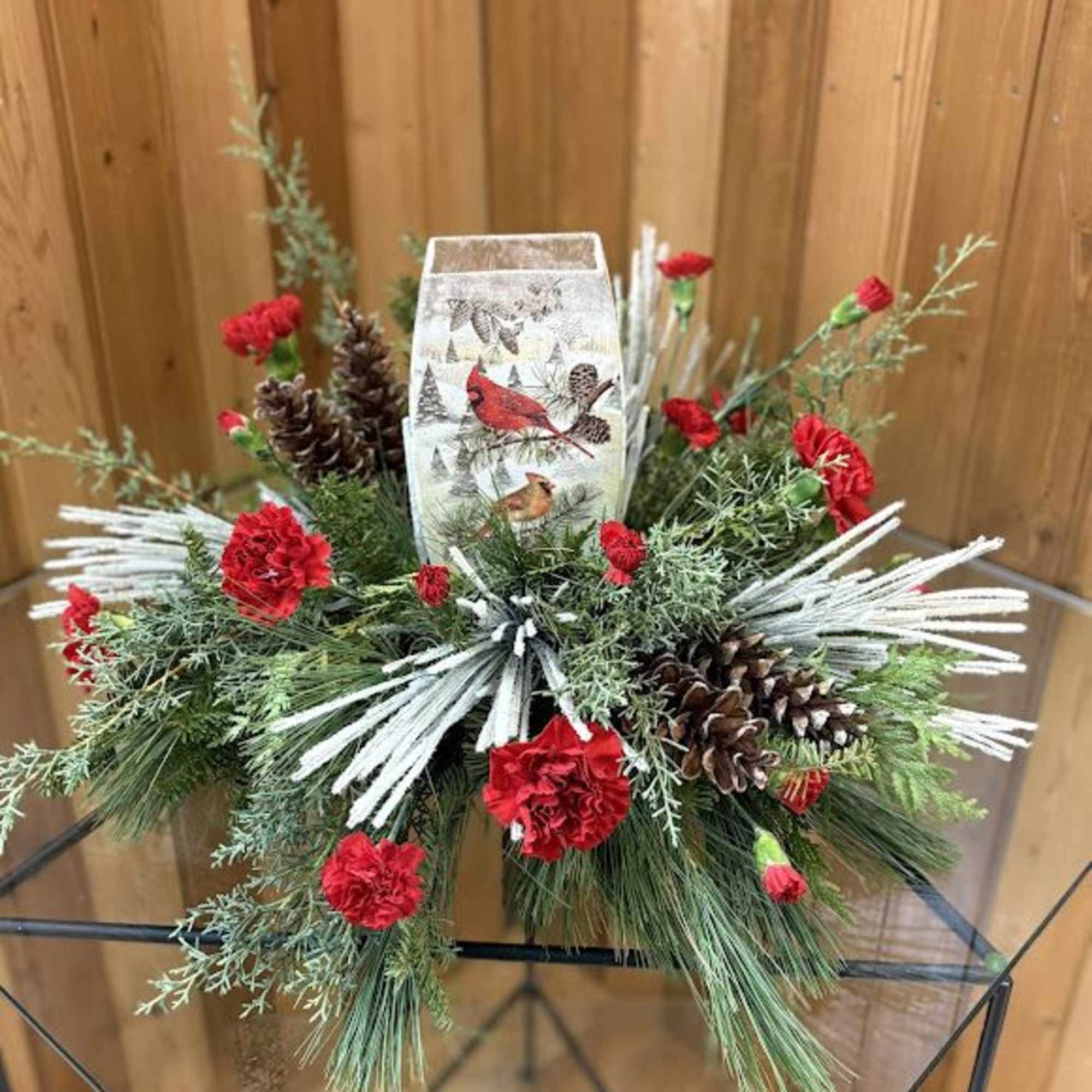 Christmas centerpiece with red carnations, pinecones, and a decorative candle holder
