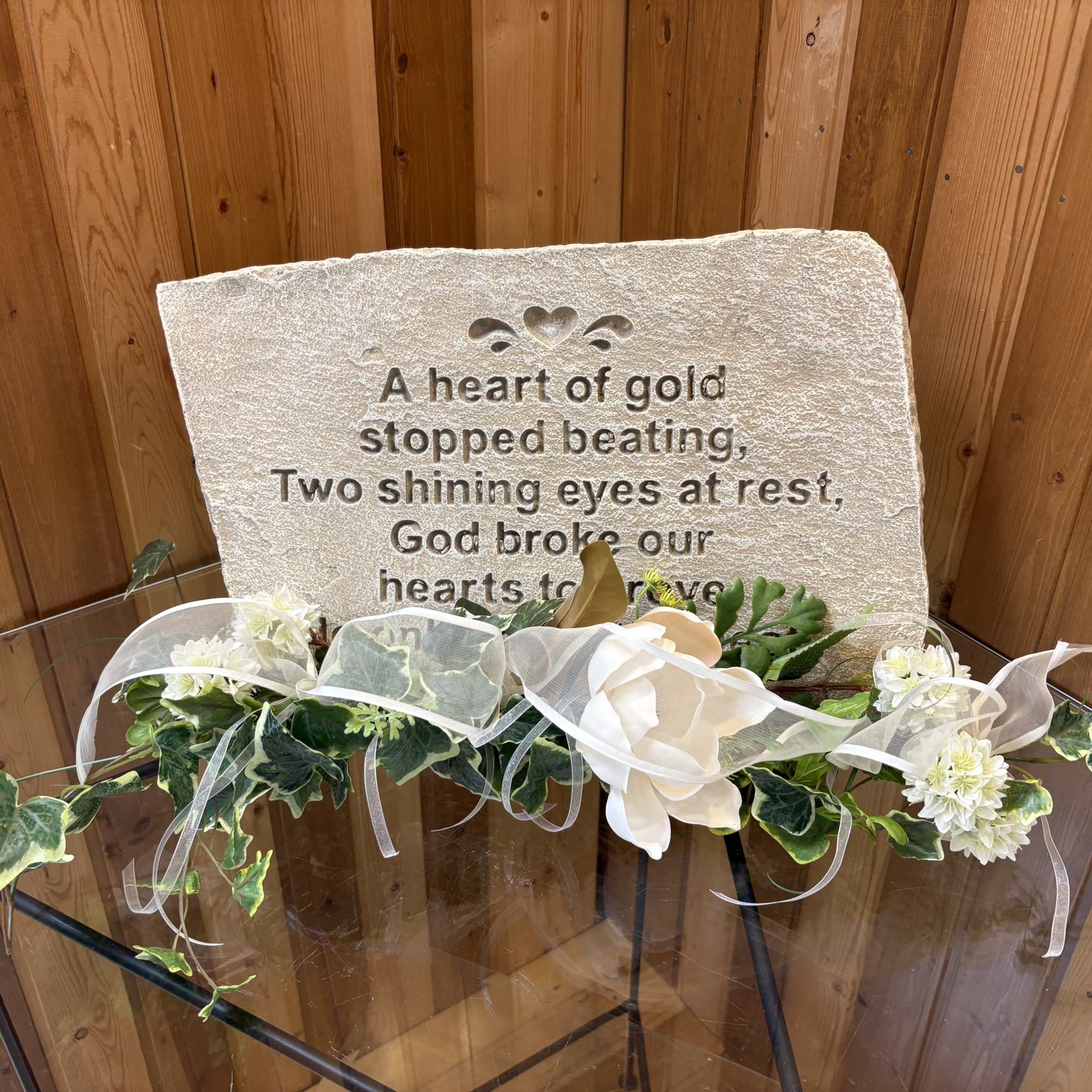 Memorial stone with white floral garland and ribbon