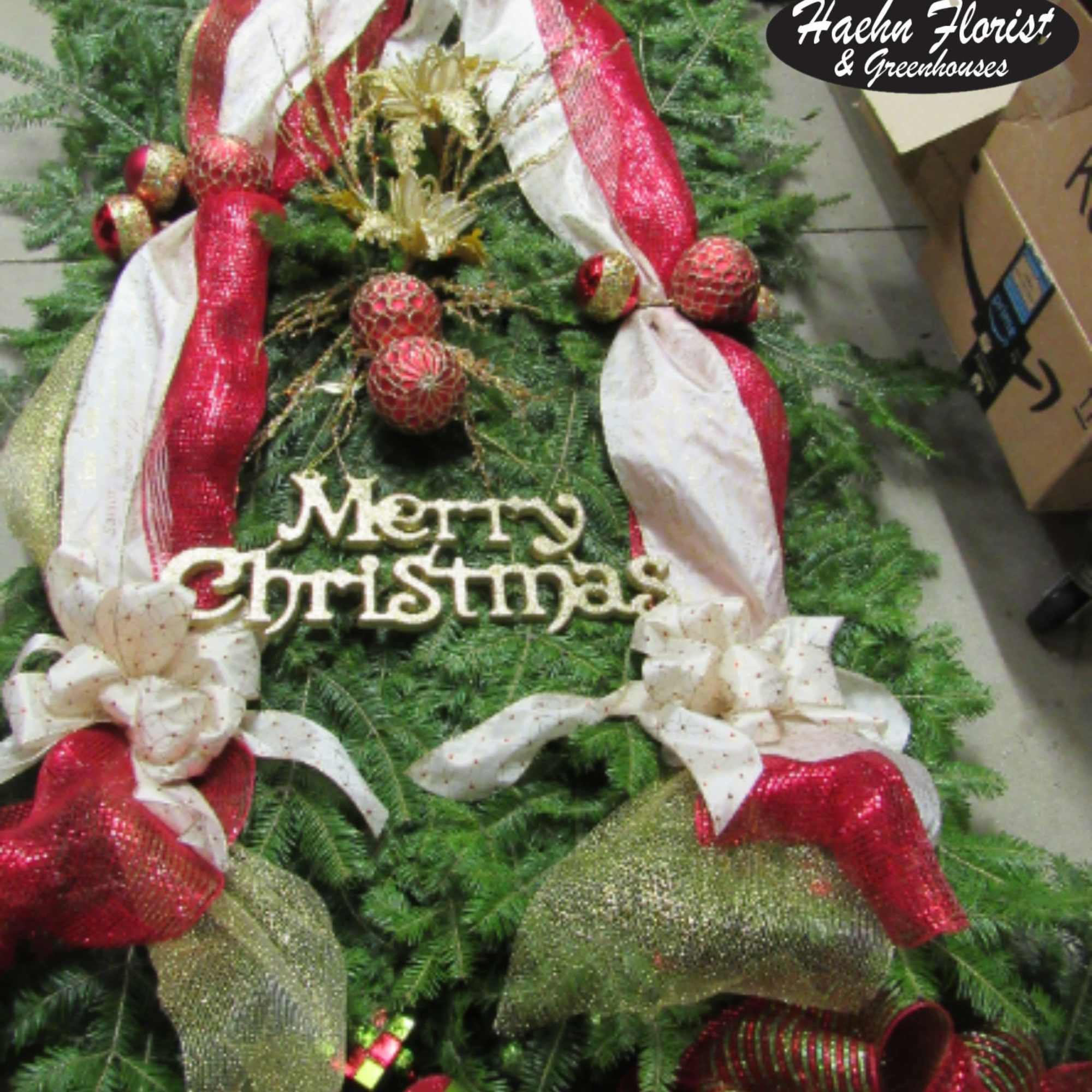 Christmas tree-shaped arrangement with red and white ribbon and a Merry Christmas sign