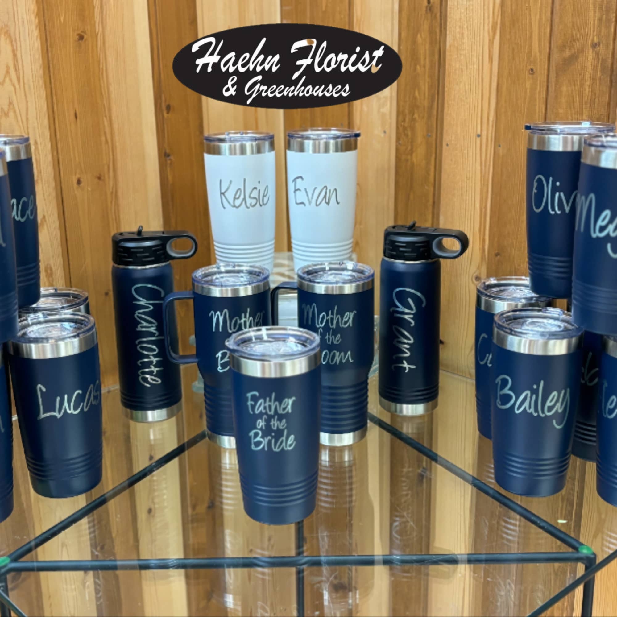 Personalized navy and white insulated tumblers displayed on a glass shelf