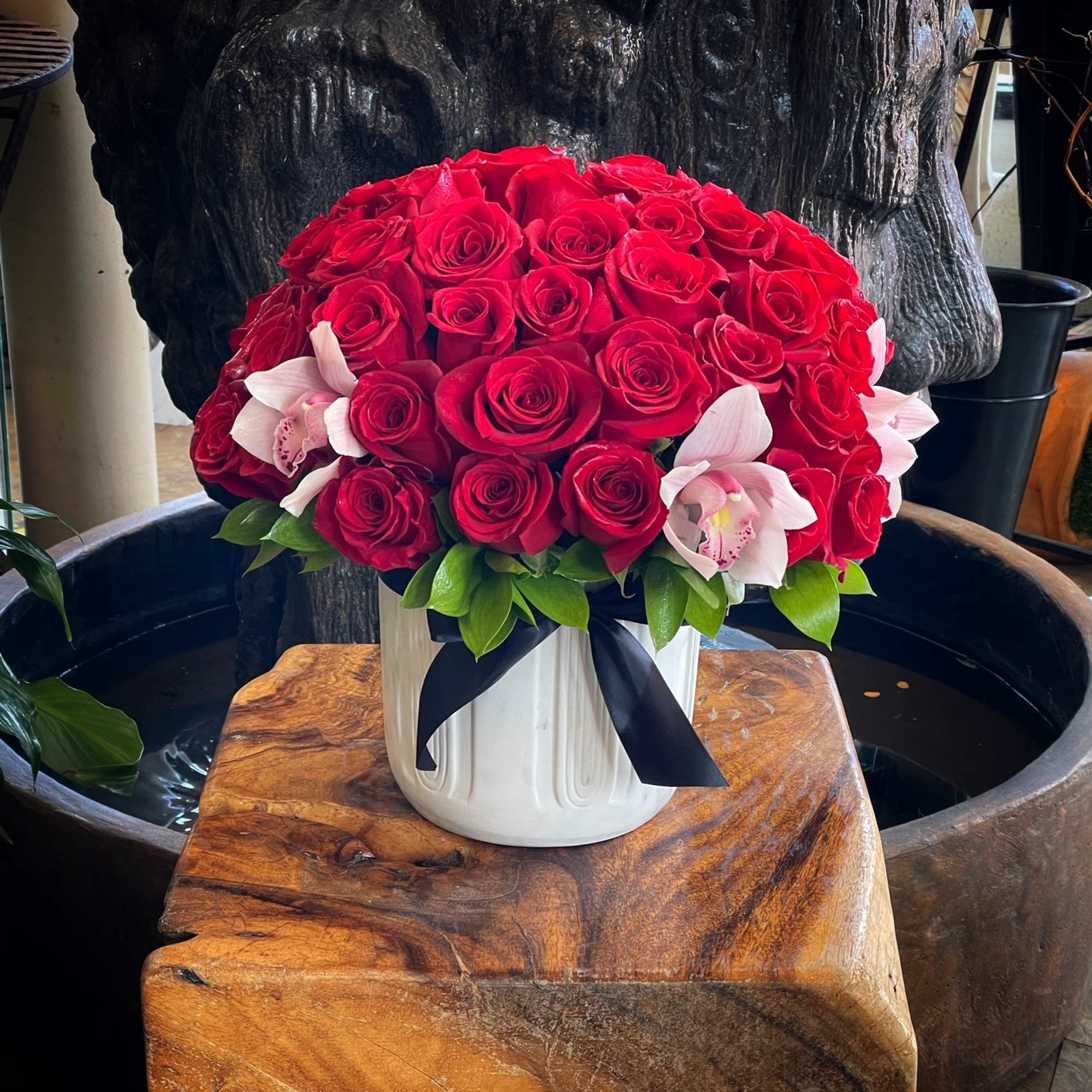 Red rose bouquet with pink orchids in a white vase