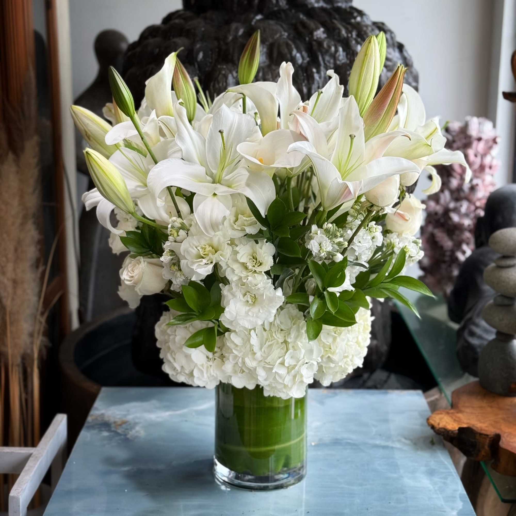 White lilies and hydrangeas arranged in a clear glass vase