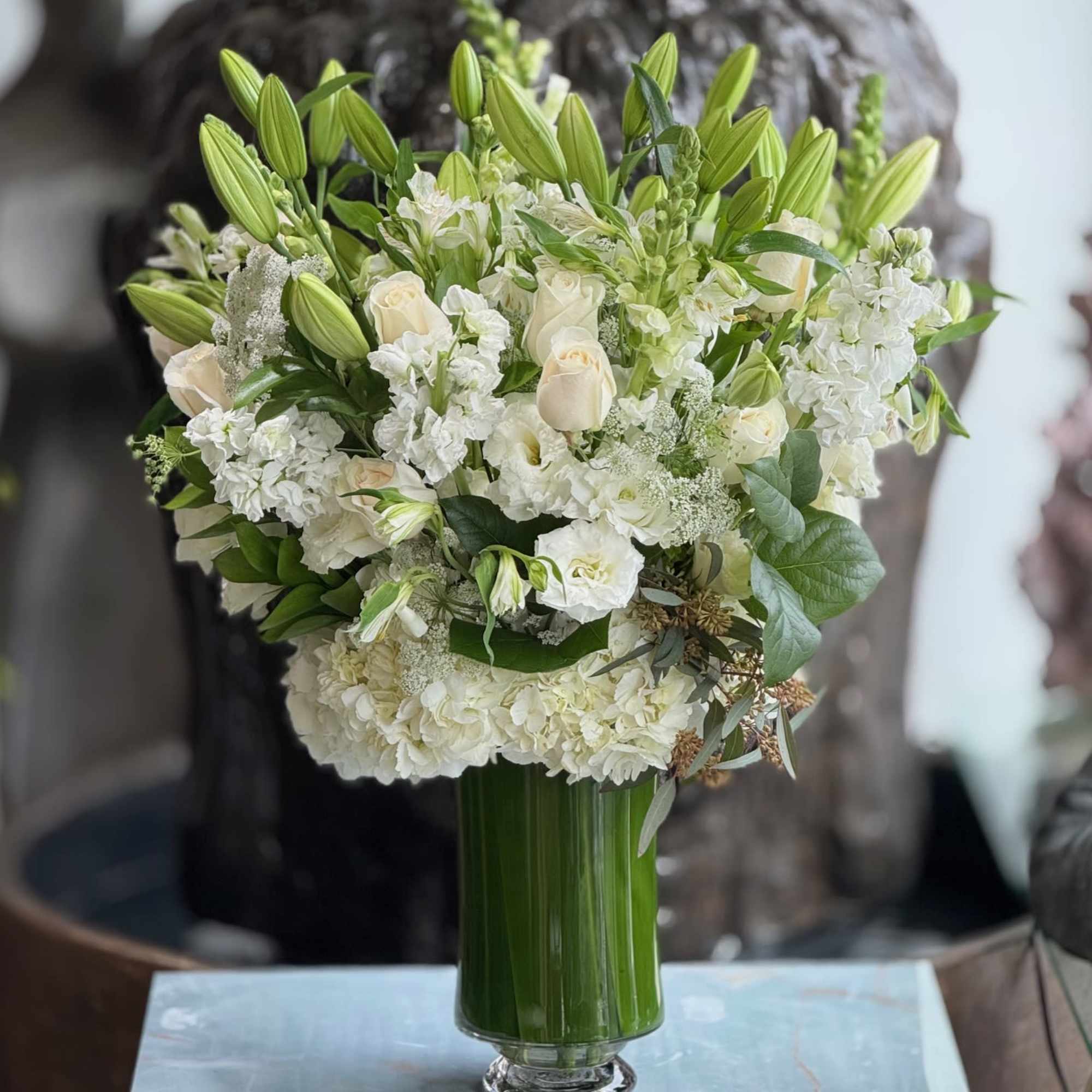 White floral bouquet in a tall green glass vase