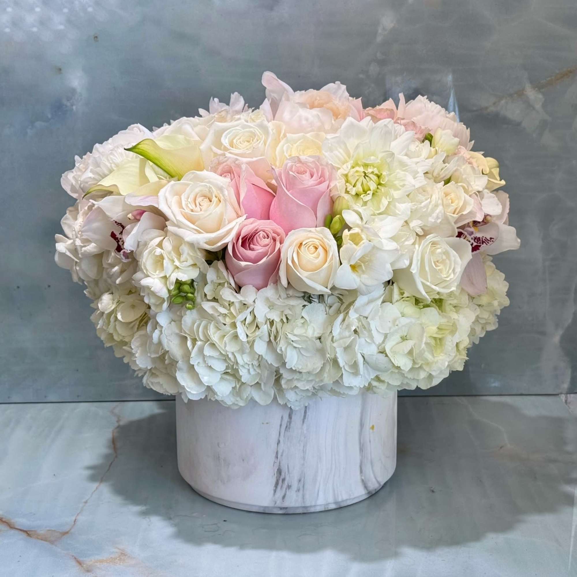 Pink and white roses arranged in a white round box