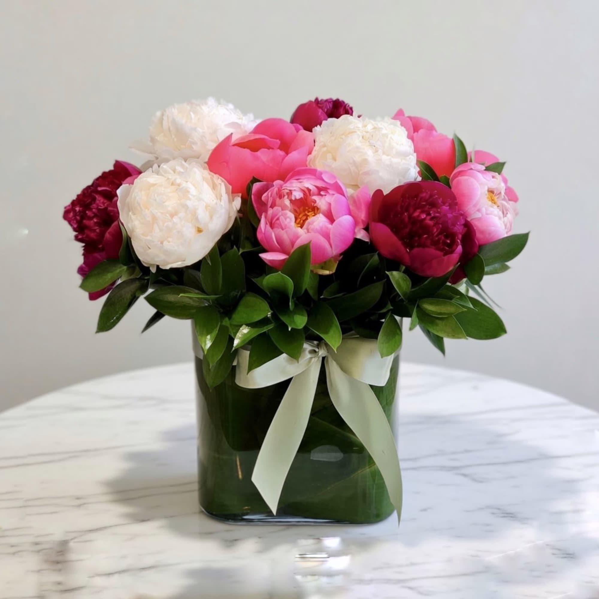 Peonies flowers in glass vase. (Substitution of Colors happen due to seasonality