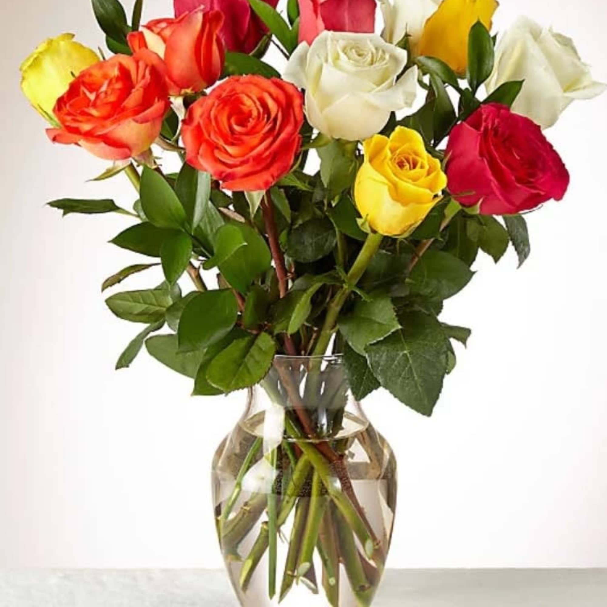 Mixed bouquet of red, yellow, white, and orange roses arranged in a clear glass vase