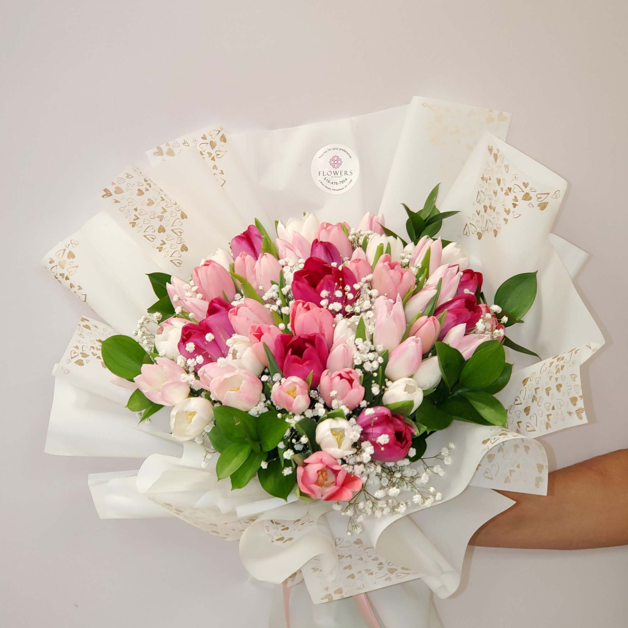 Hand-tied bouquet of pink and white tulips wrapped in white paper