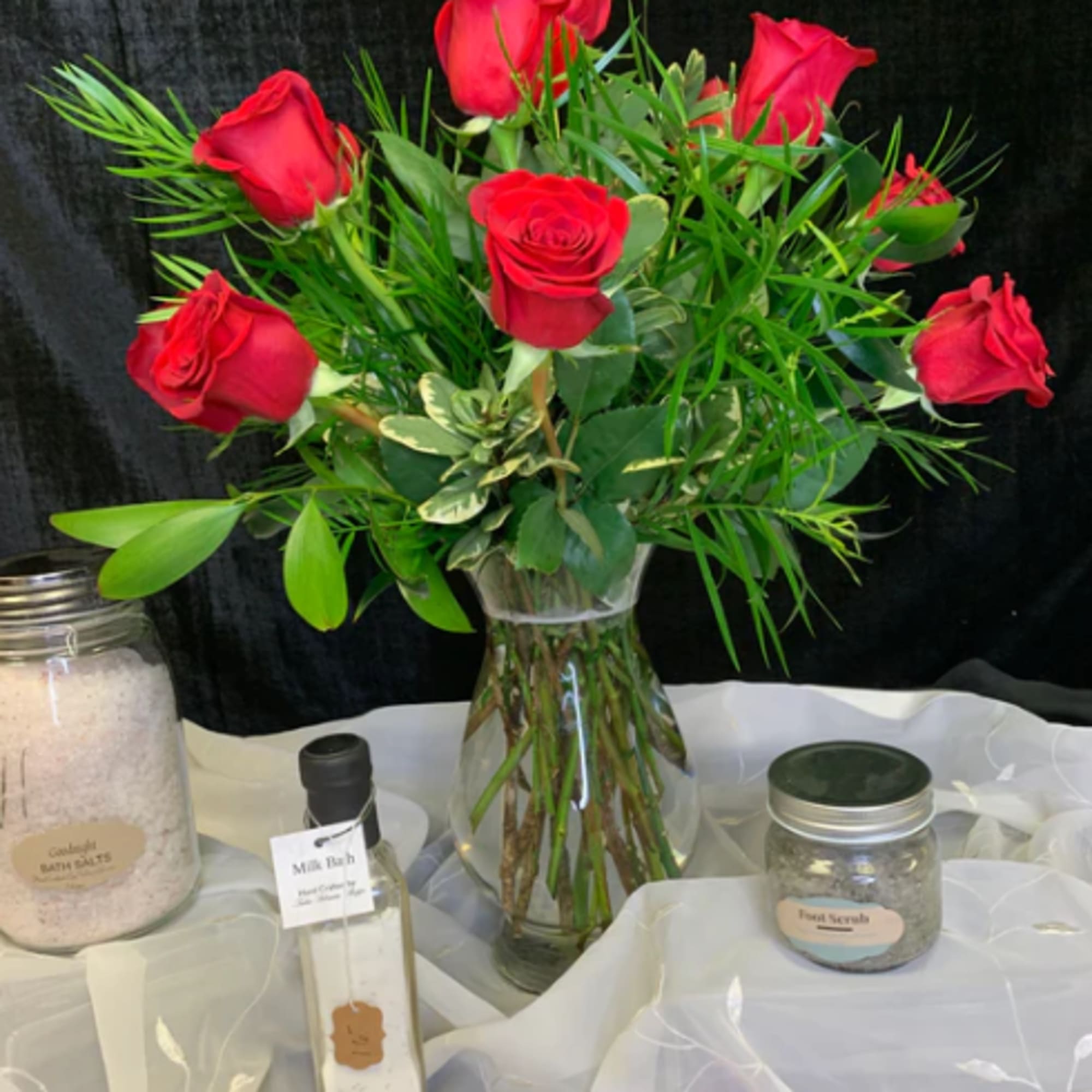 Red roses arranged in a clear glass vase with greenery