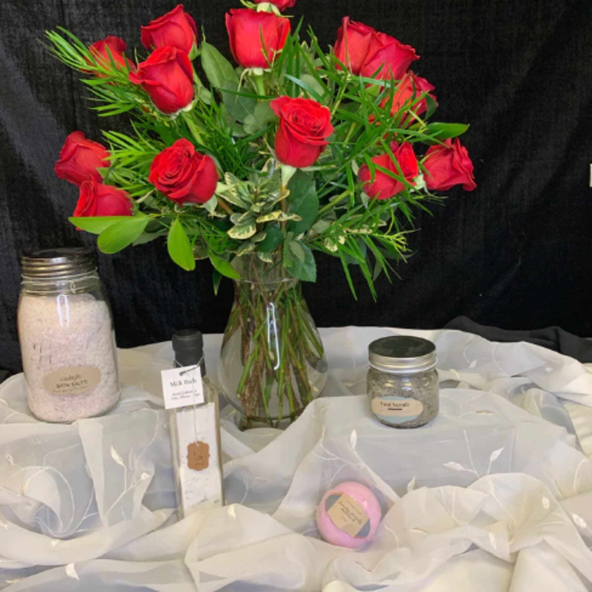Red roses arranged in a clear glass vase with greenery