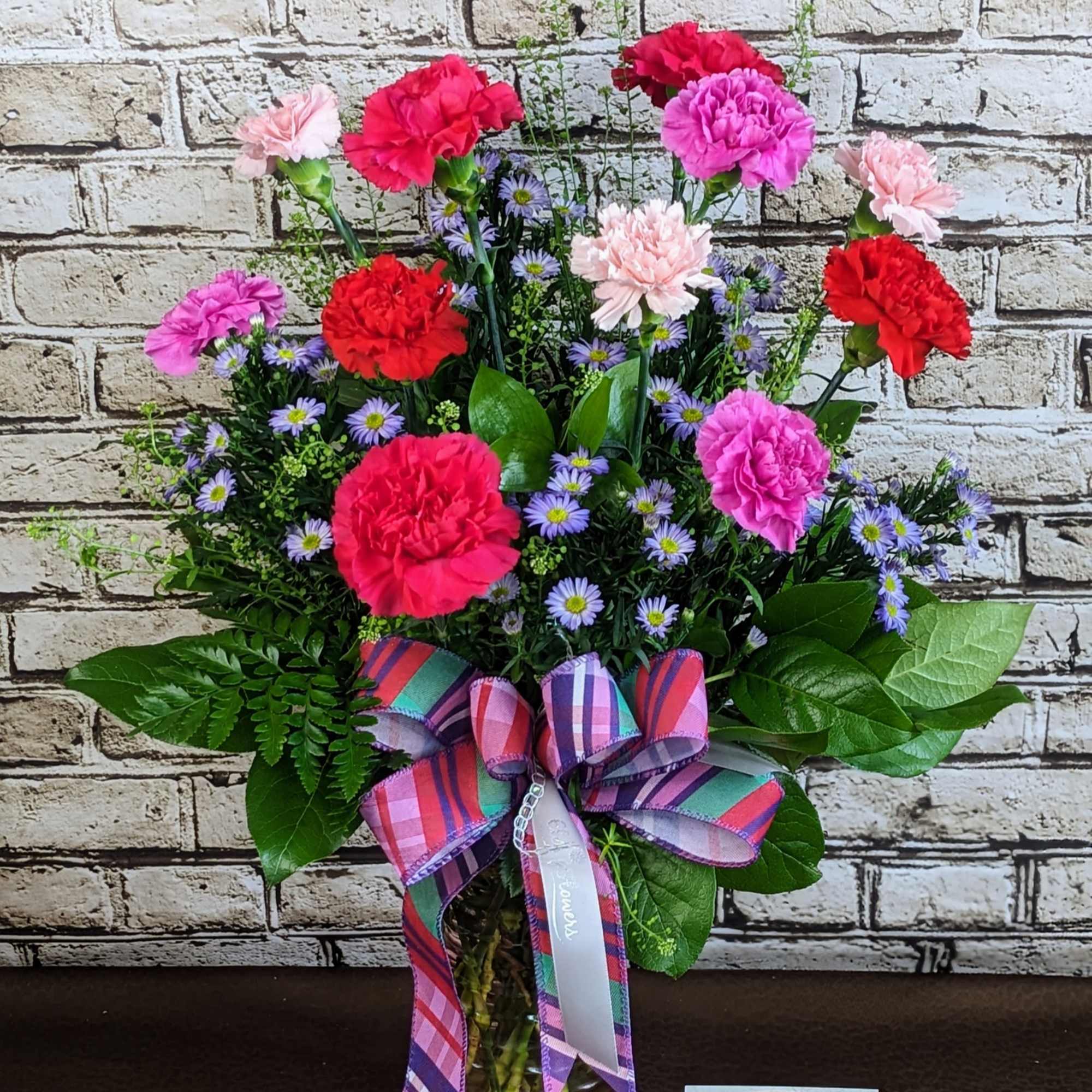 Carnation bouquet in a glass vase with a plaid ribbon