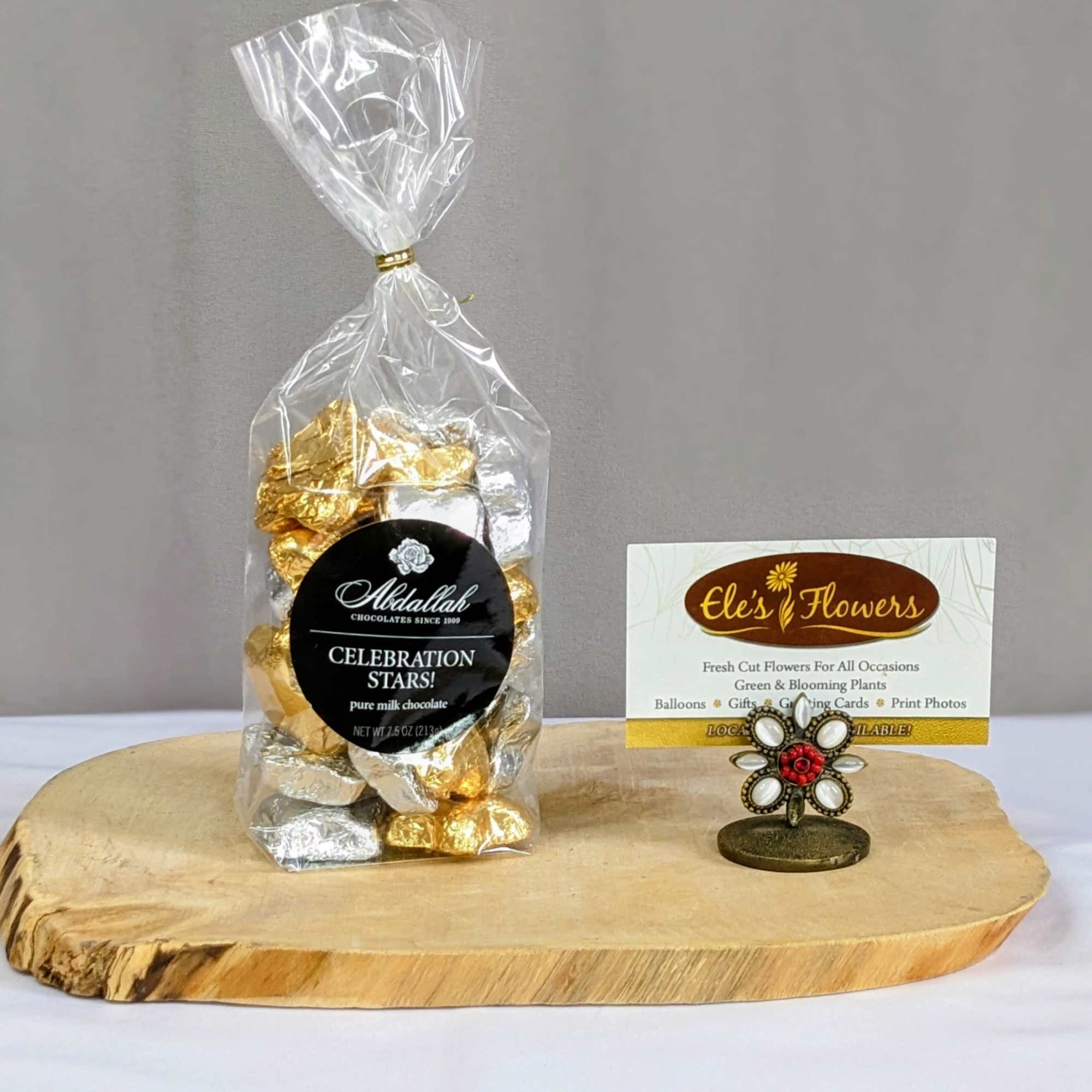 Bag of gold and silver wrapped chocolates with a business card holder on a wooden board