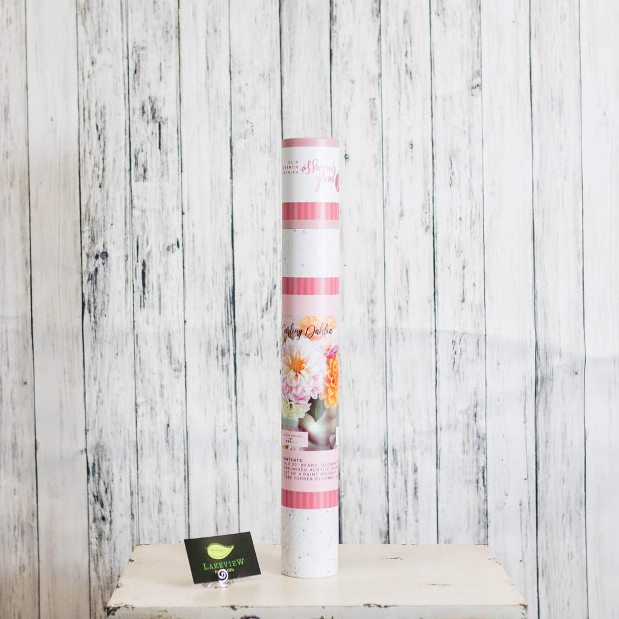 Tall floral craft kit tube with pink accents on a white wooden surface