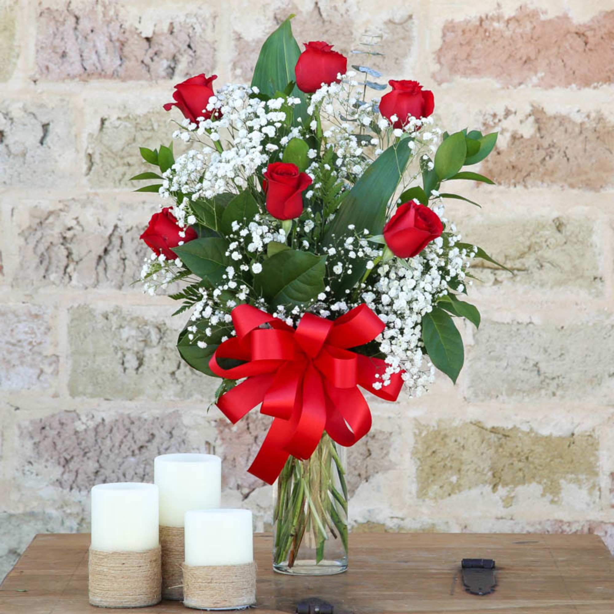 Bouquet of red roses with baby's breath in a glass vase and red ribbon