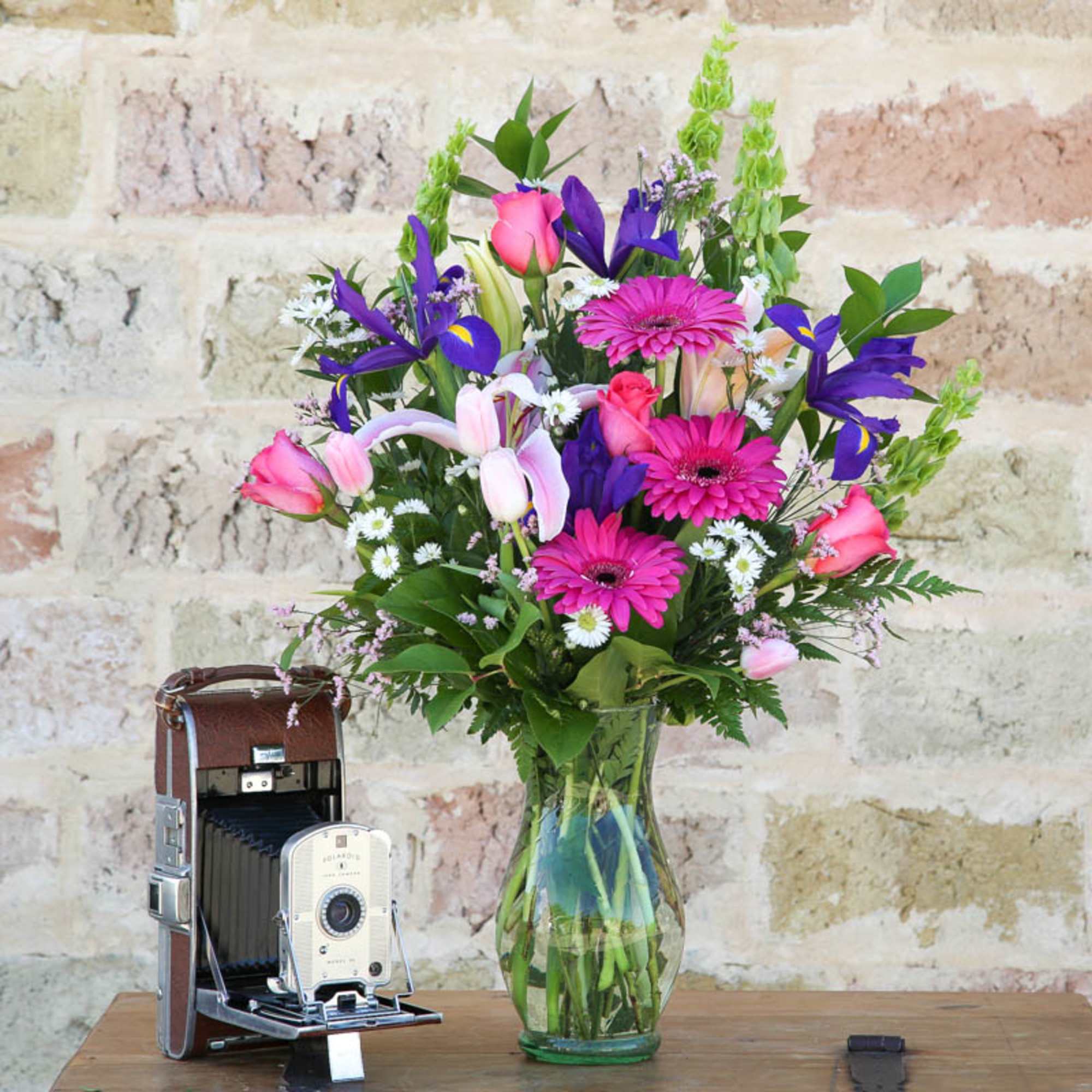 Mixed bouquet of pink, purple, and white flowers in a glass vase