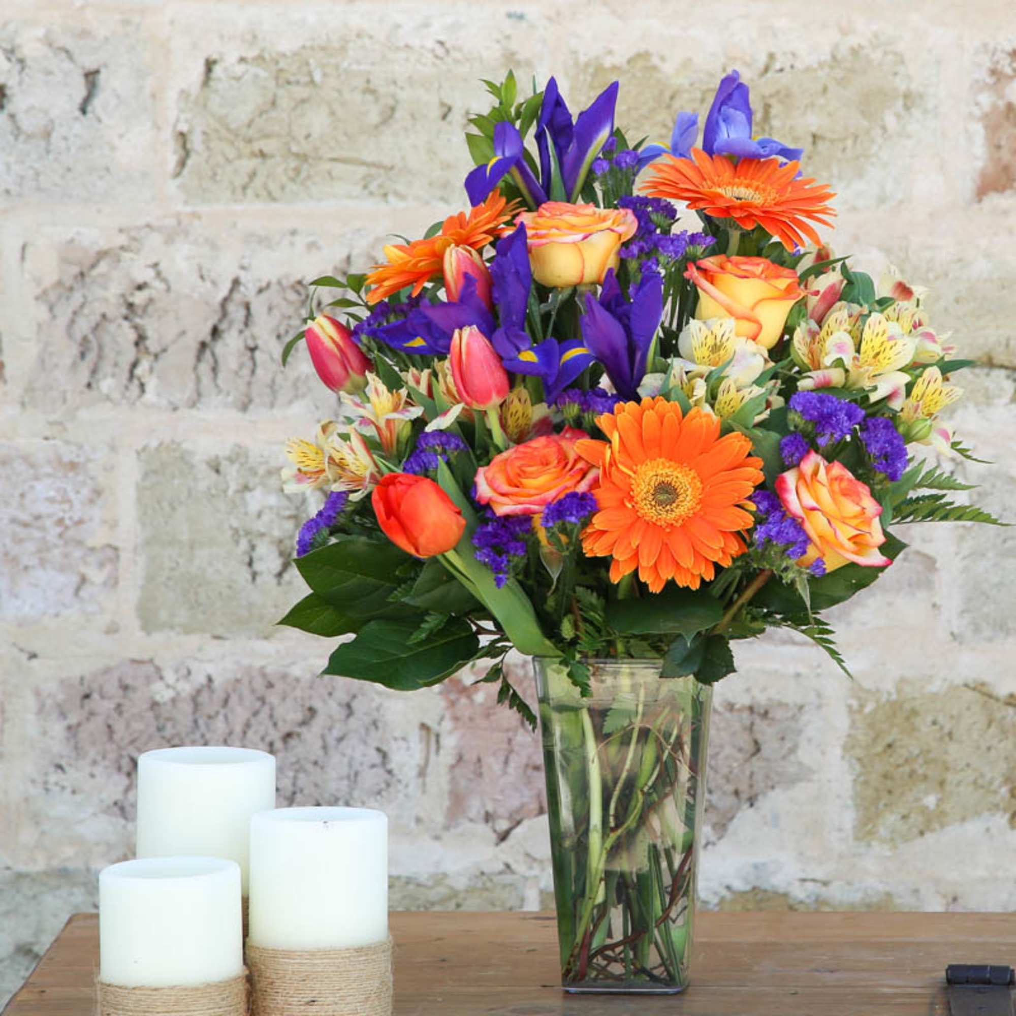 Colorful bouquet of orange, purple, and pink flowers in a glass vase