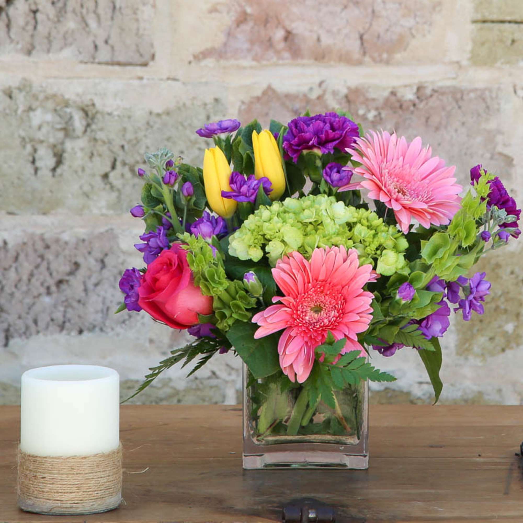 Mixed bouquet in a square glass vase with pink gerberas and purple blooms