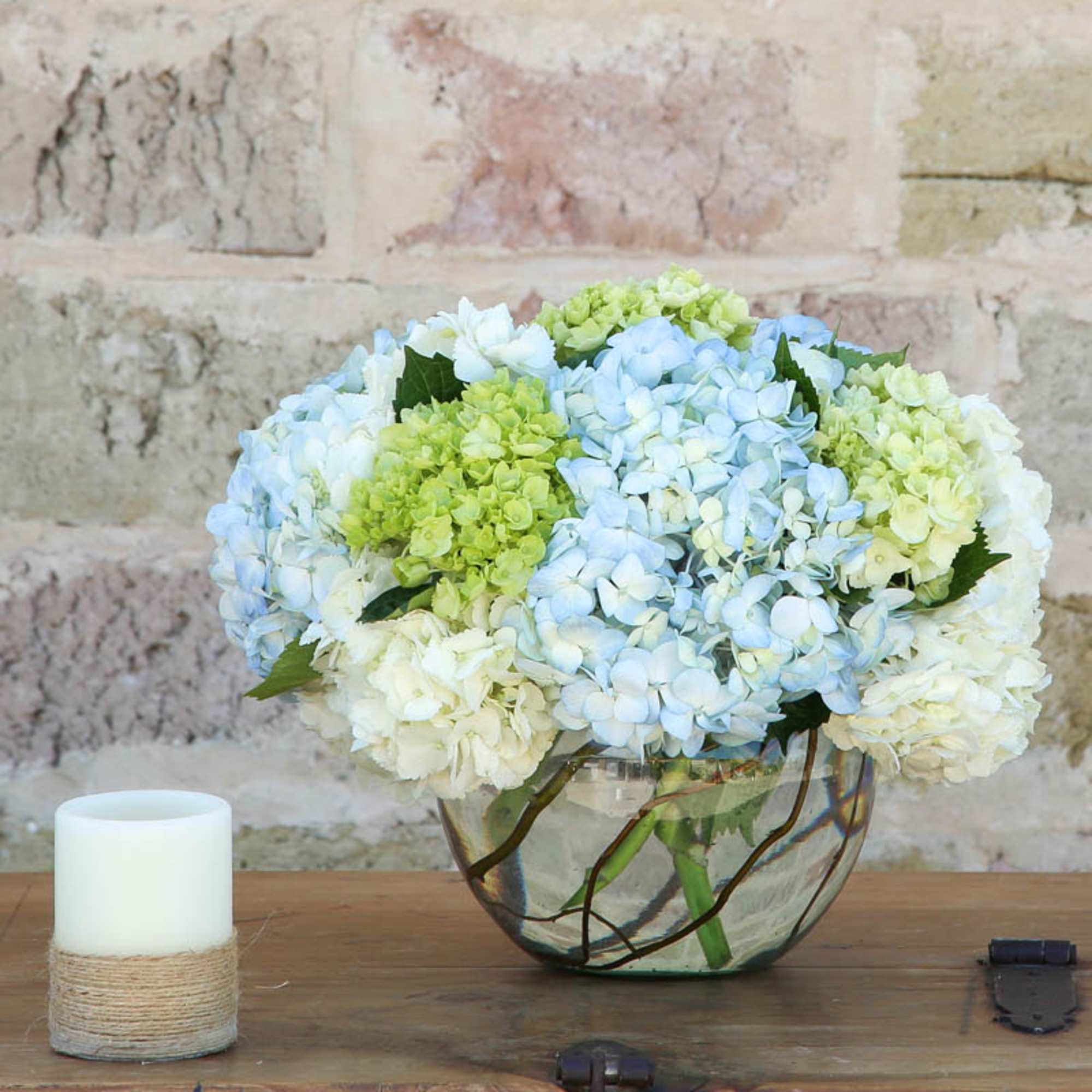 Blue and white hydrangea arrangement in a glass bowl vase