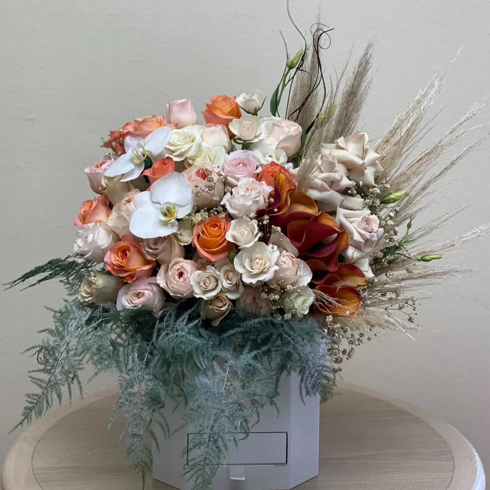 Large bouquet of pastel roses and orchids in a white box
