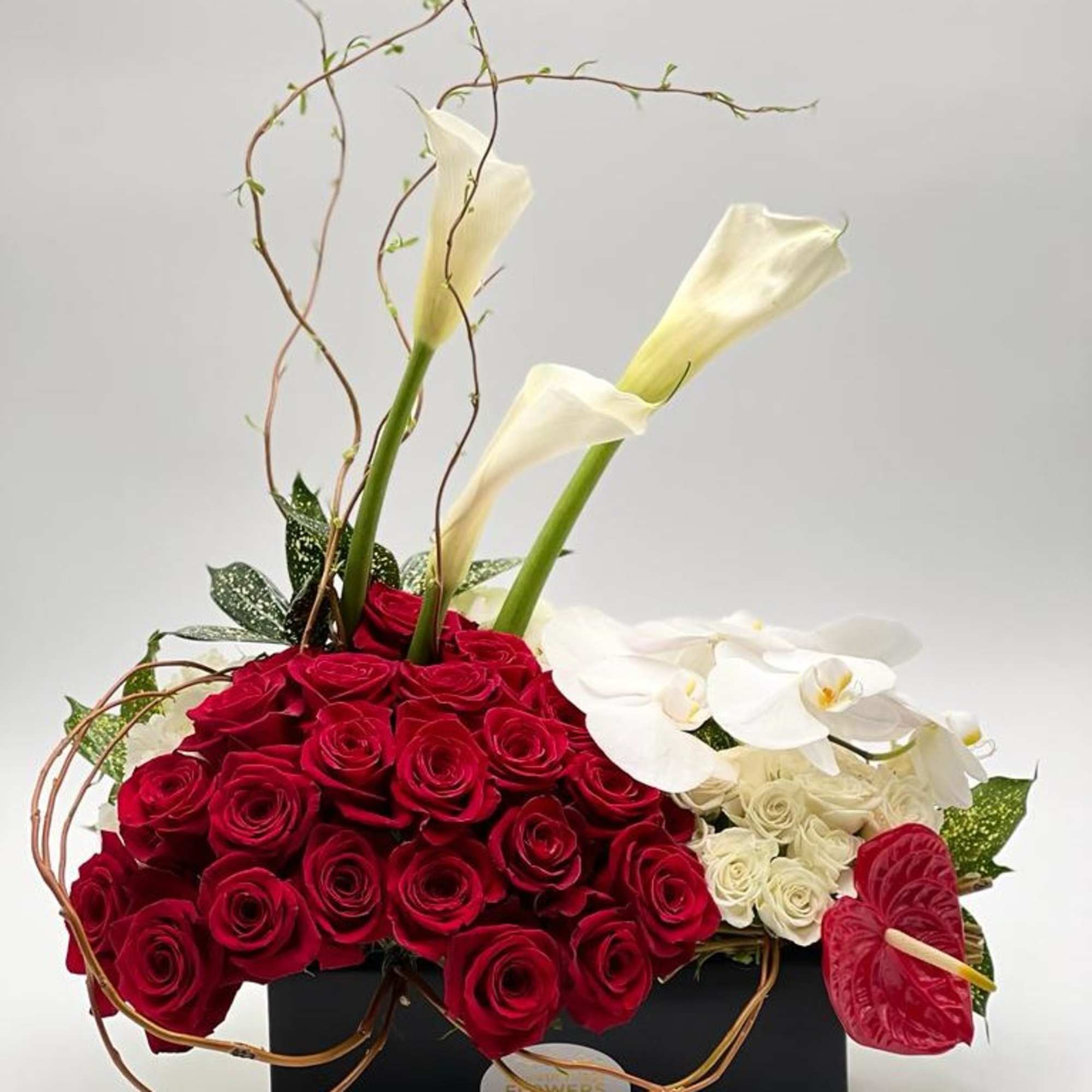 Red roses with white calla lilies and orchids in a black box