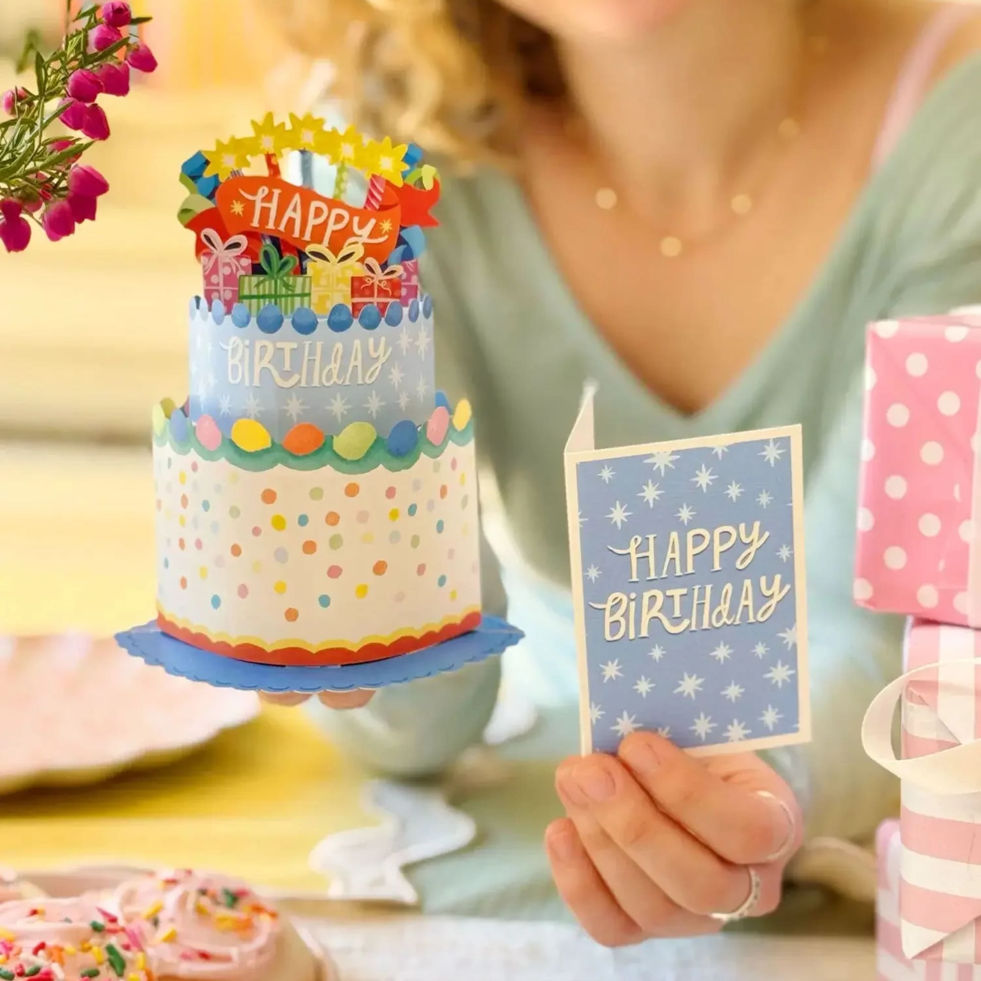 Woman holding a birthday card and a decorated cake with flowers