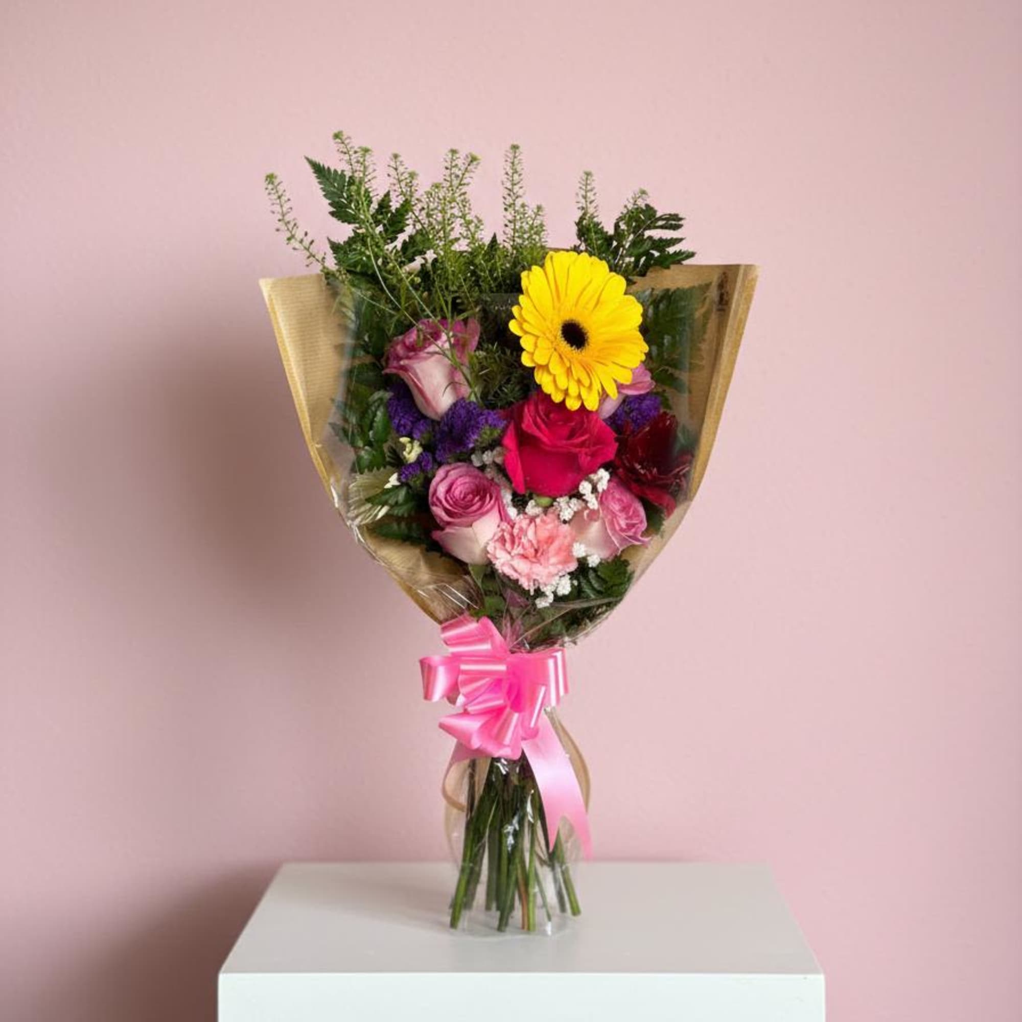 Mixed bouquet with pink and yellow flowers wrapped in clear paper