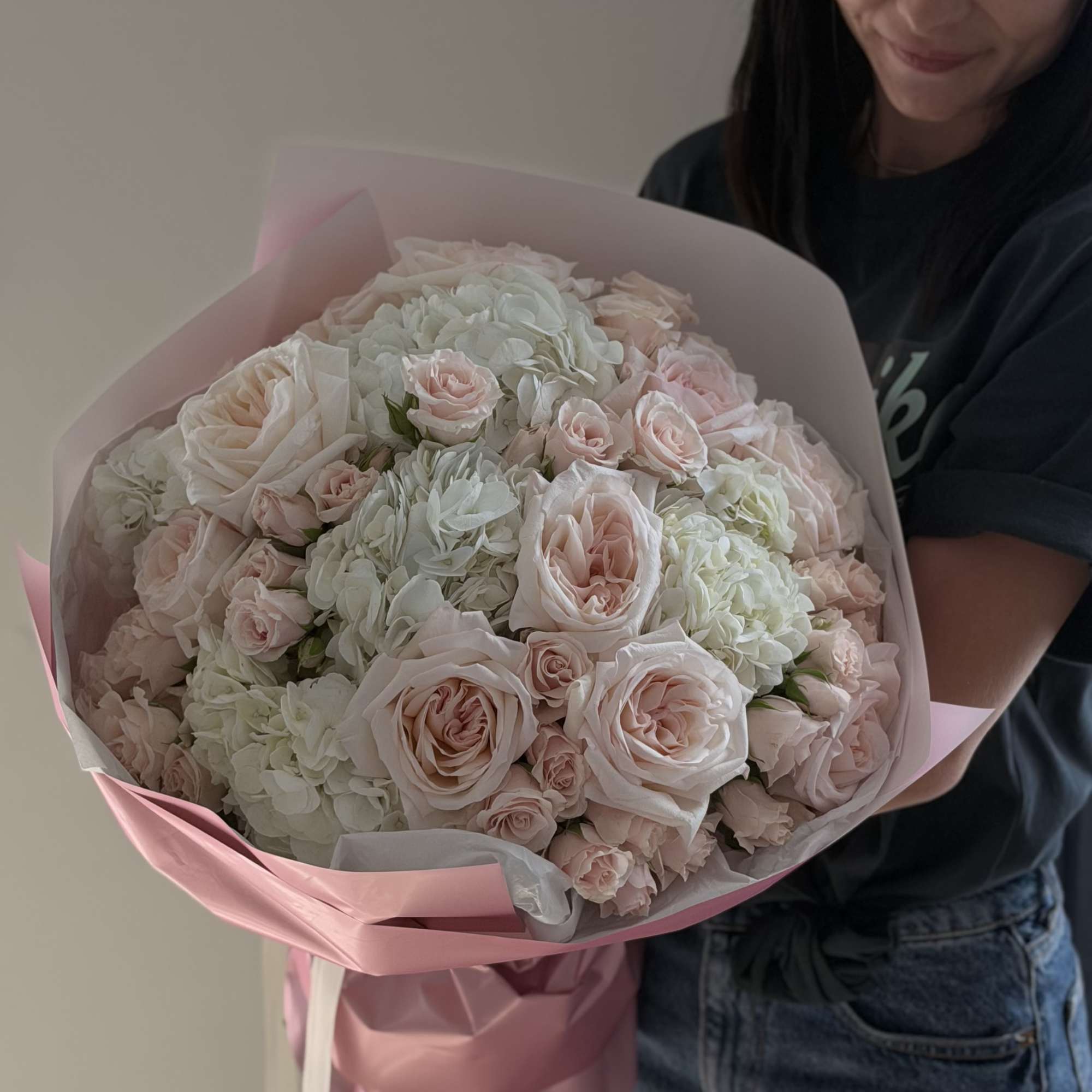 Large bouquet of pale pink roses and white hydrangeas wrapped in pink paper